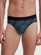 Herren-Model trägt Slip mit Softgummibund aus Baumwolle in Schwarz, Gemustert aus Serie Grafic Cotton von CALIDA, Vorderansicht