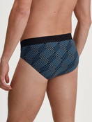 Herren-Model trägt Slip mit Softgummibund aus Baumwolle in Schwarz, Gemustert aus Serie Grafic Cotton von CALIDA, Rückansicht