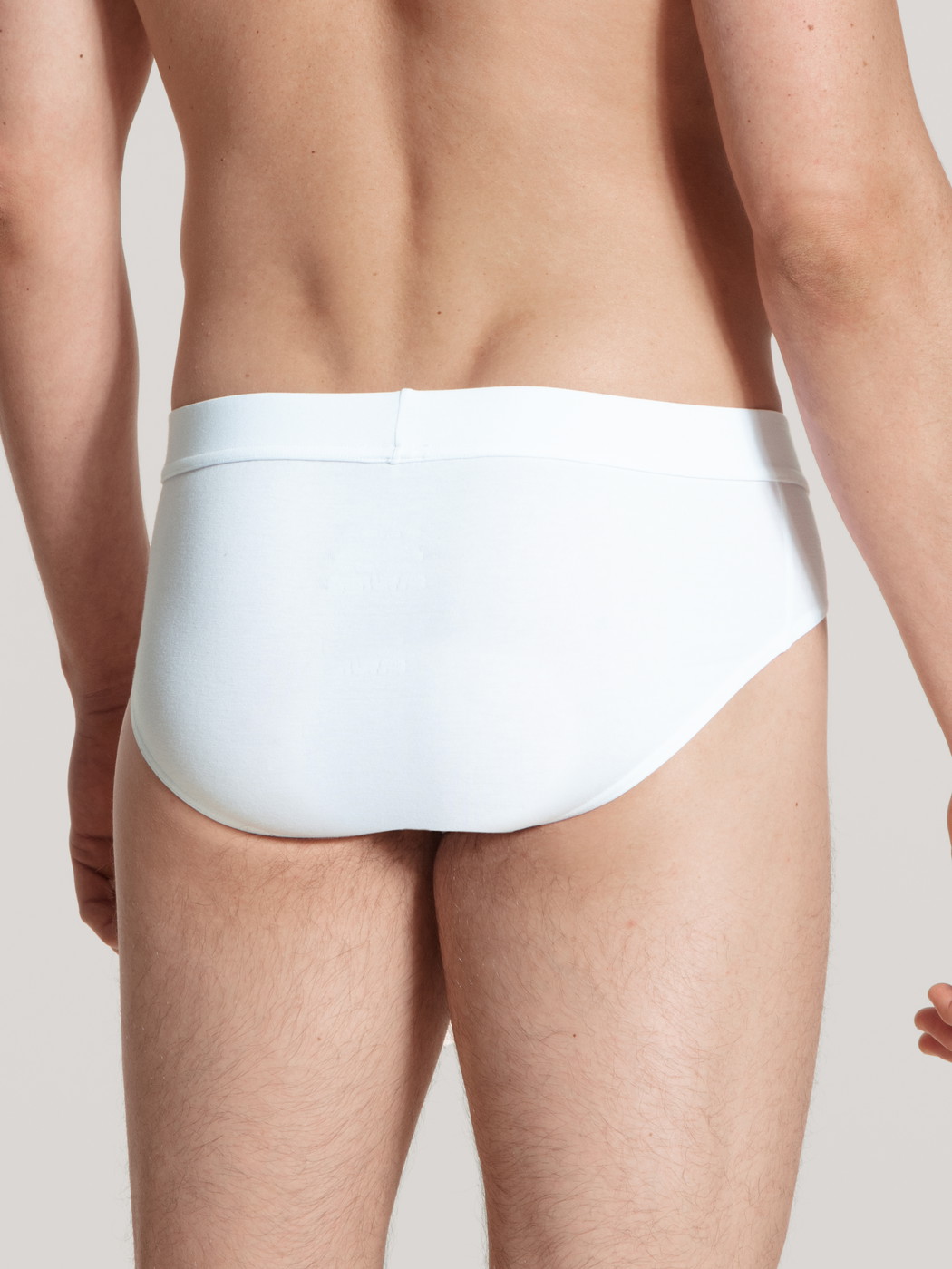 Herren-Model trägt Slip, Komfortbund aus Baumwolle in Weiß, Einfarbig aus Serie Cotton Code von CALIDA, Rückansicht