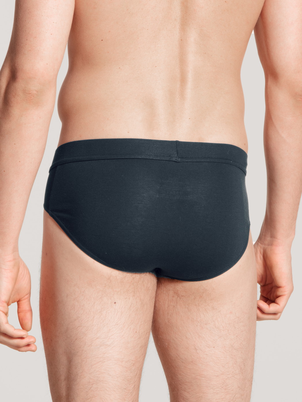 Herren-Model trägt Slip, Komfortbund aus Baumwolle in Blau, Einfarbig aus Serie Cotton Code von CALIDA, Rückansicht
