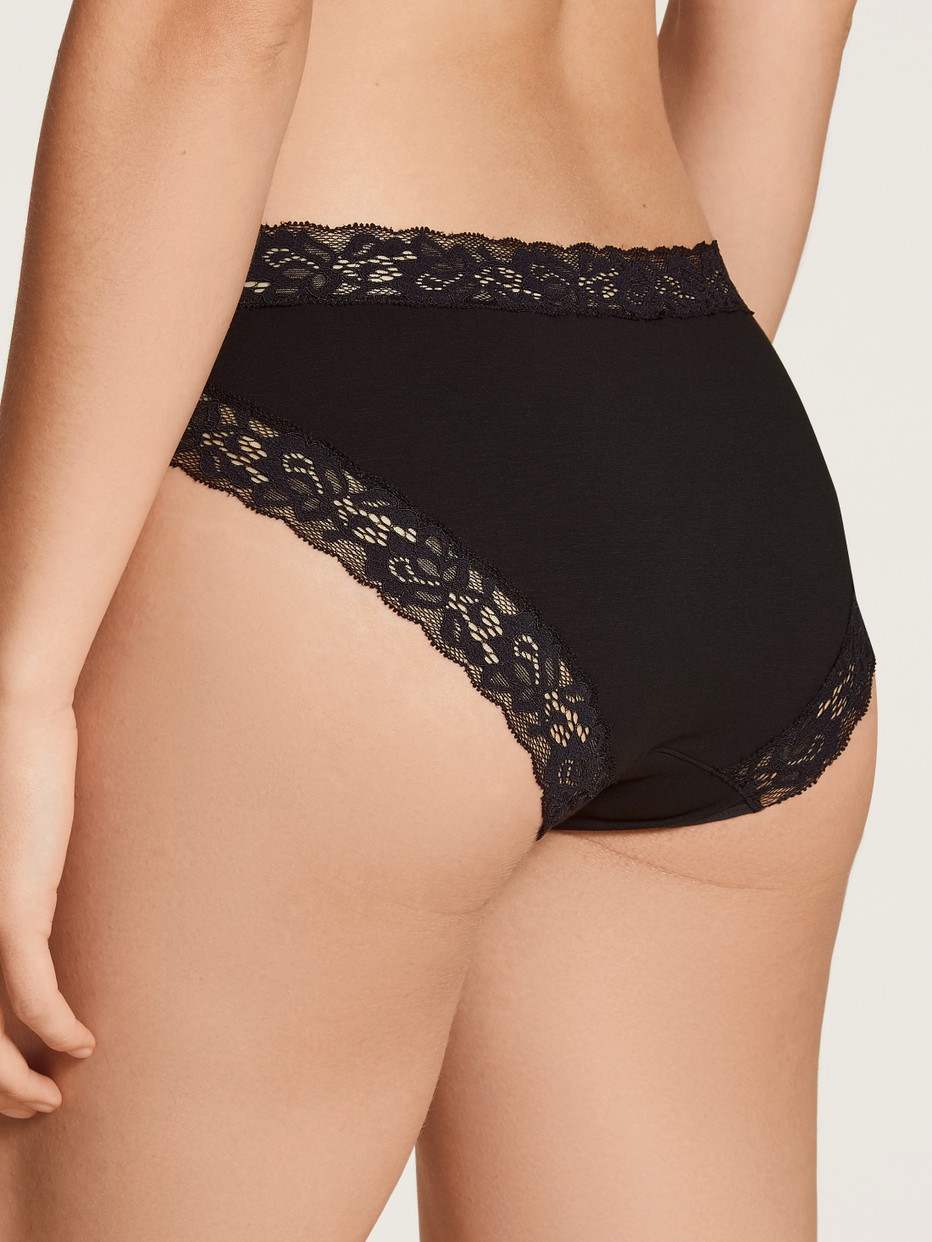 Damen-Model trägt Slip, regular cut aus Baumwolle in Schwarz, Spitze aus Serie Natural Comfort Lace von CALIDA, Rückansicht