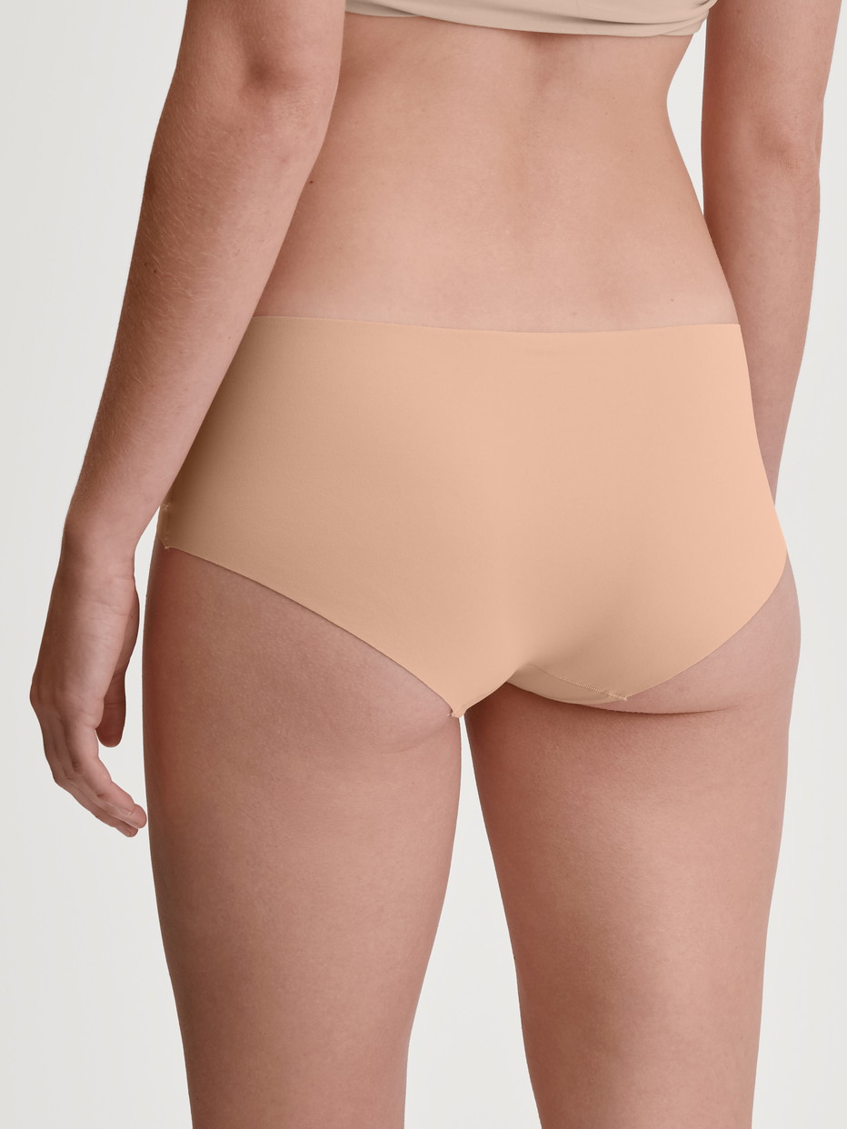 Damen-Model trägt Nahtlose Hipster-Panty Clean-Cut aus Polyamid in Beige, Einfarbig aus Serie Sleek Skin von CALIDA, Rückansicht