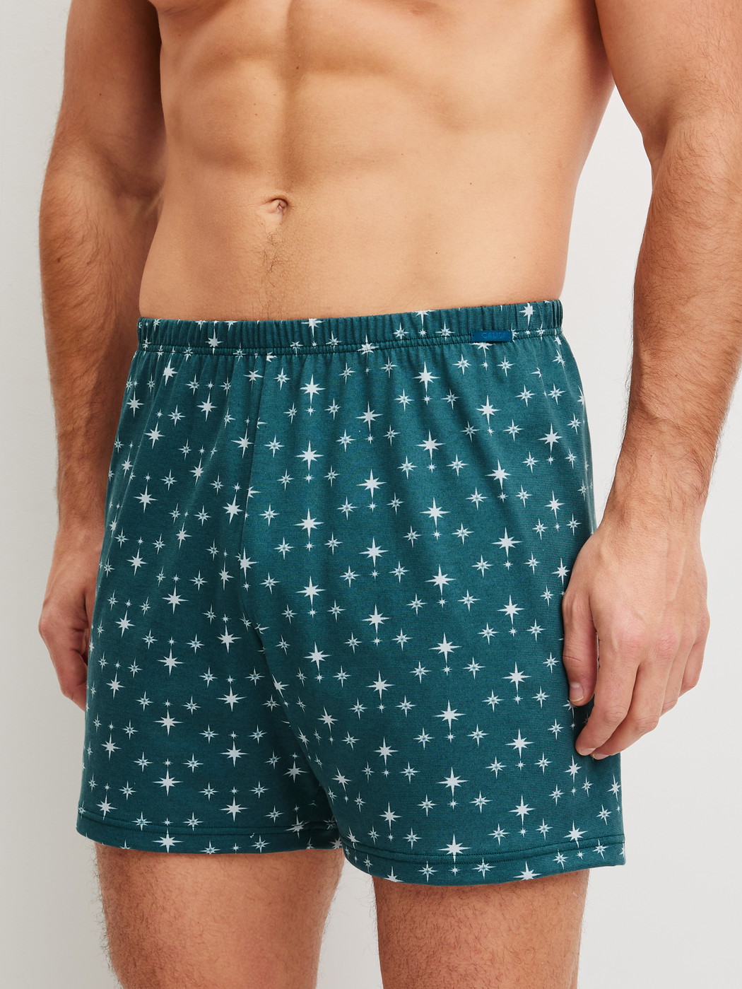 Men model is wearing Boxer shorts made of 100% Cotton in Turquoise, Patterned from the Prints series by CALIDA, Front view