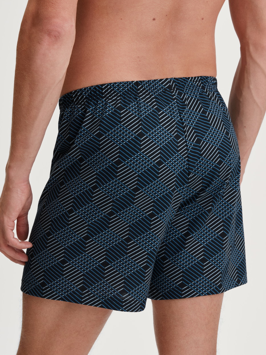 Men model is wearing Boxer shorts made of 100% Cotton in Black, Patterned from the Prints series by CALIDA, Back view