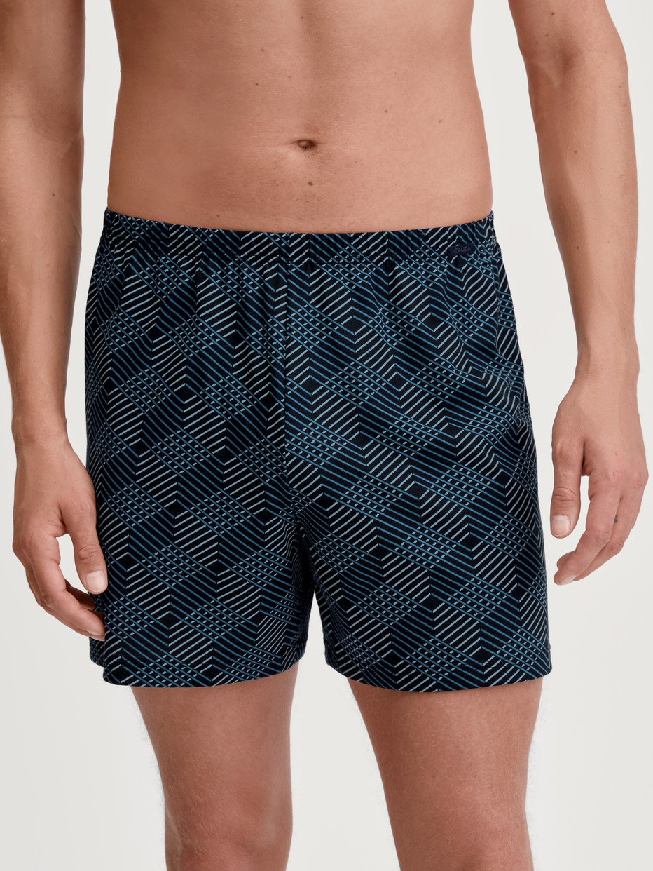 Herren-Model trägt Jersey-Boxershorts ohne Eingriff aus 100% Baumwolle in Schwarz, Gemustert aus Serie Prints von CALIDA, Vorderansicht