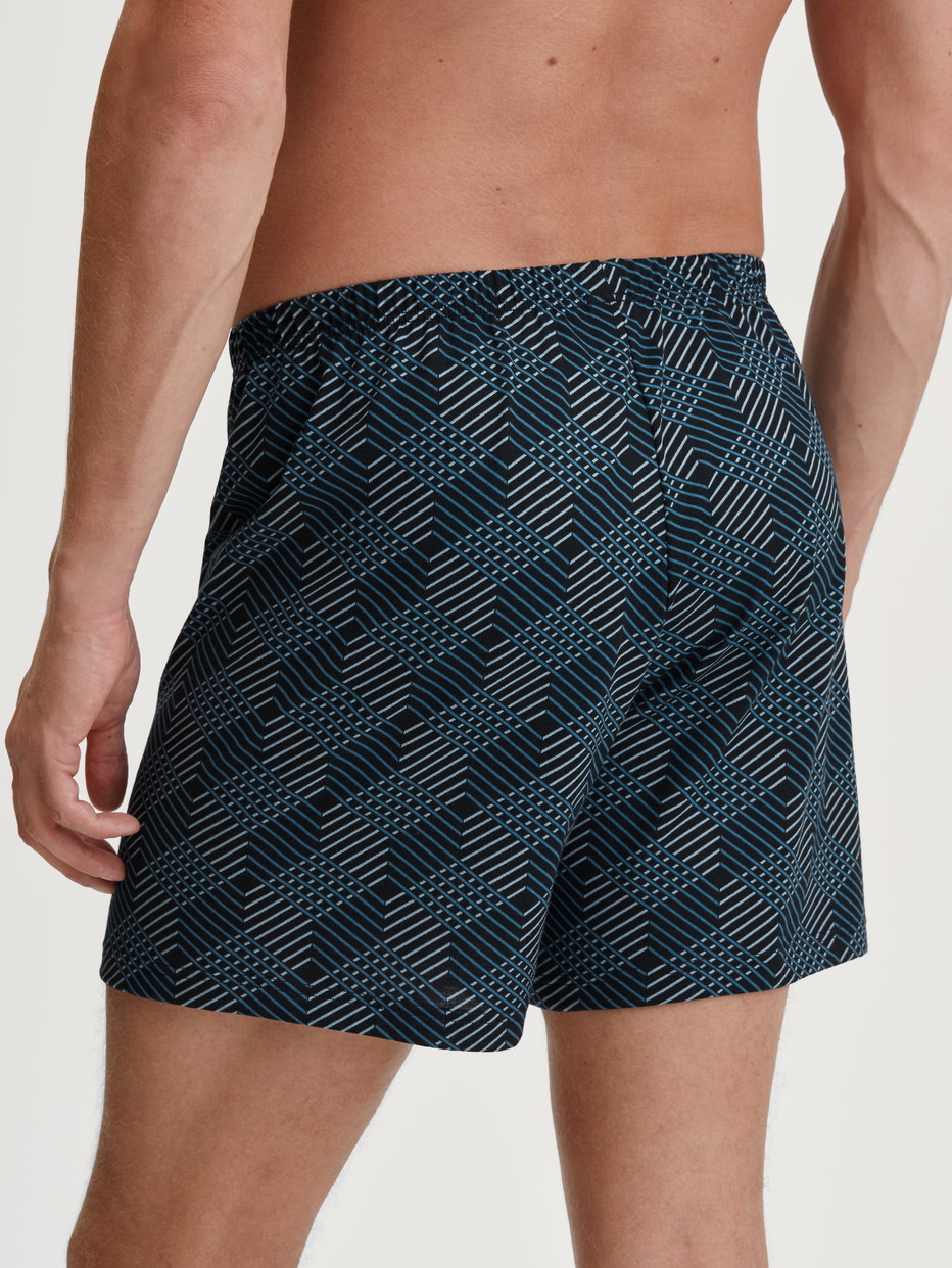 Herren-Model trägt Jersey-Boxershorts ohne Eingriff aus 100% Baumwolle in Schwarz, Gemustert aus Serie Prints von CALIDA, Rückansicht