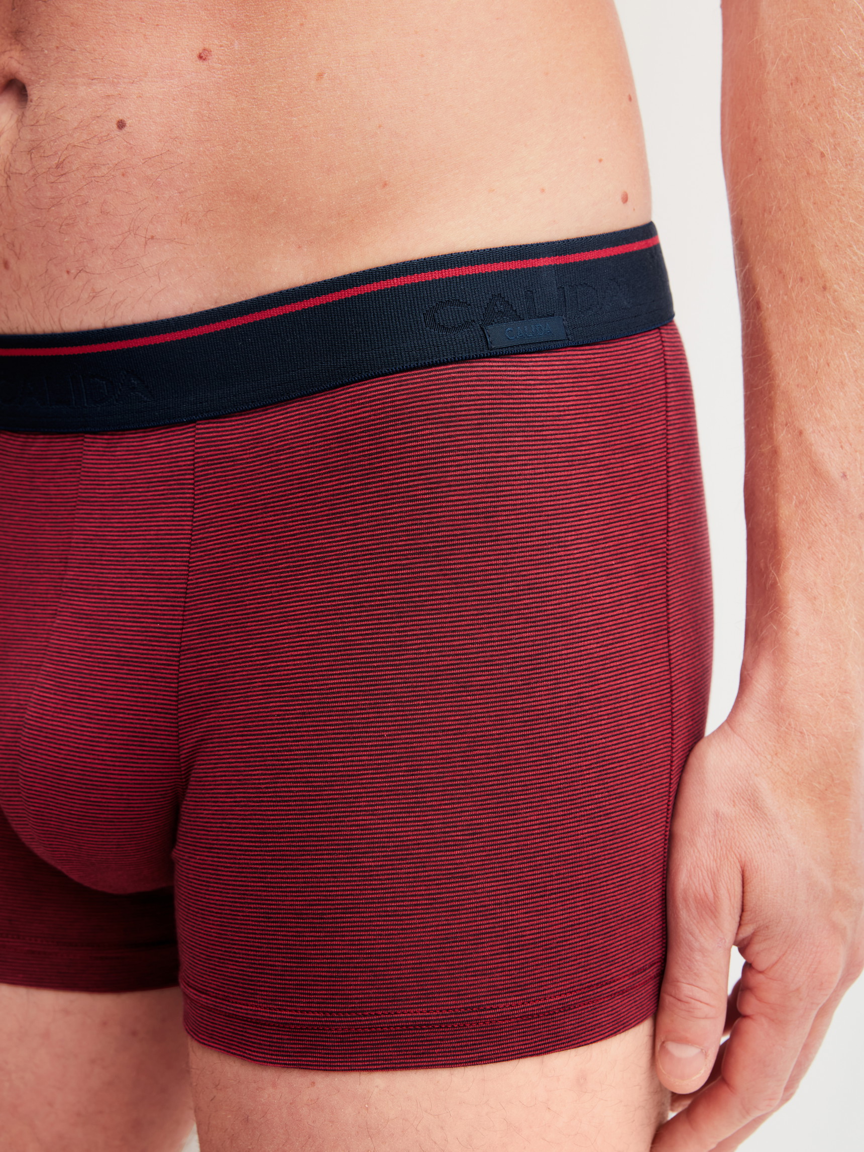 La modella / Il modello Uomo indossa Boxer brief in Cotone di colore Rosso, Tinta unita, della serie Cotton Stretch di CALIDA, Dettaglio
