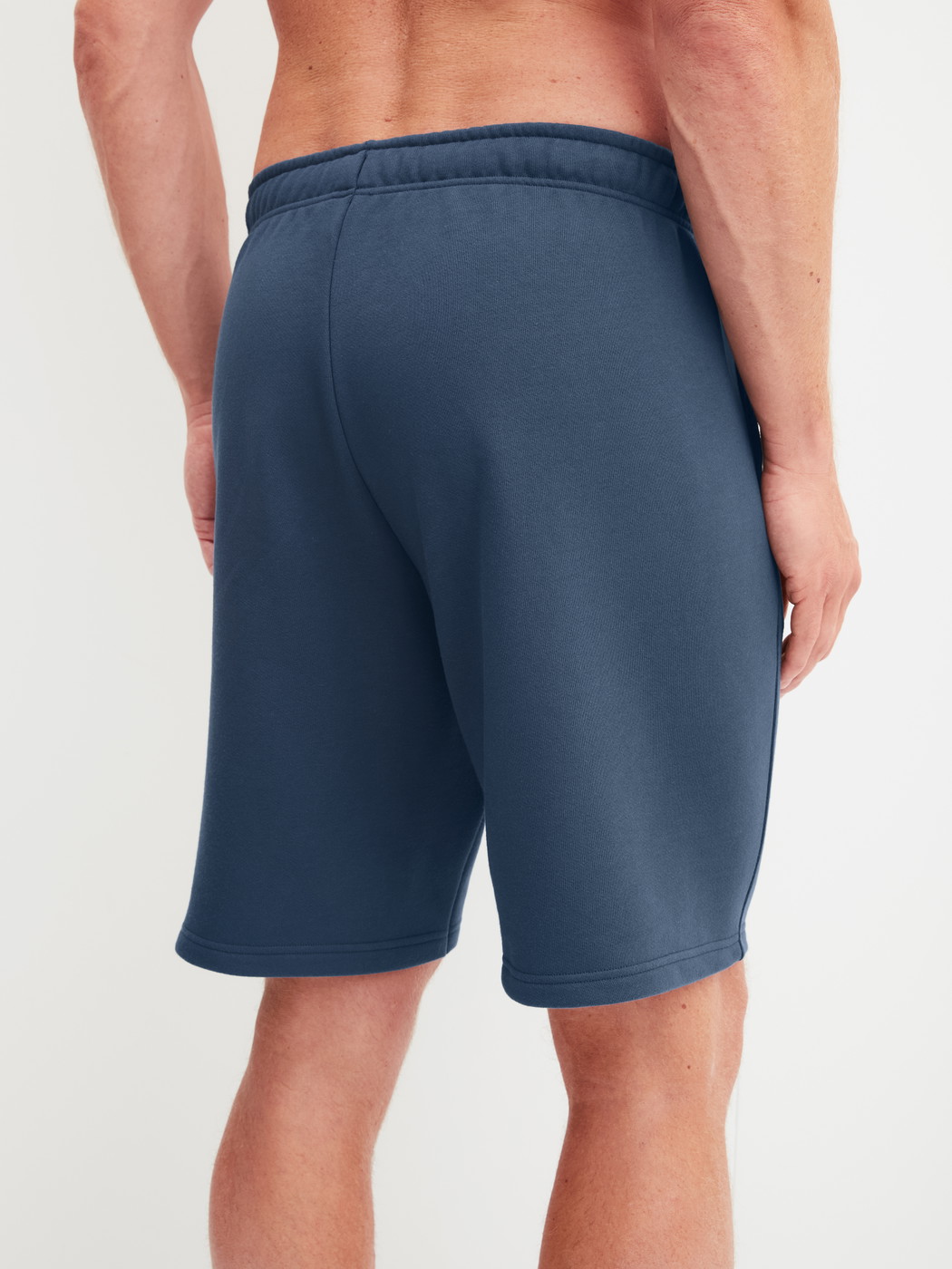 Herren-Model trägt Bermudas mit Seitentaschen aus Baumwolle in Blau, Einfarbig aus Serie RMX Lounge Journey von CALIDA, Rückansicht