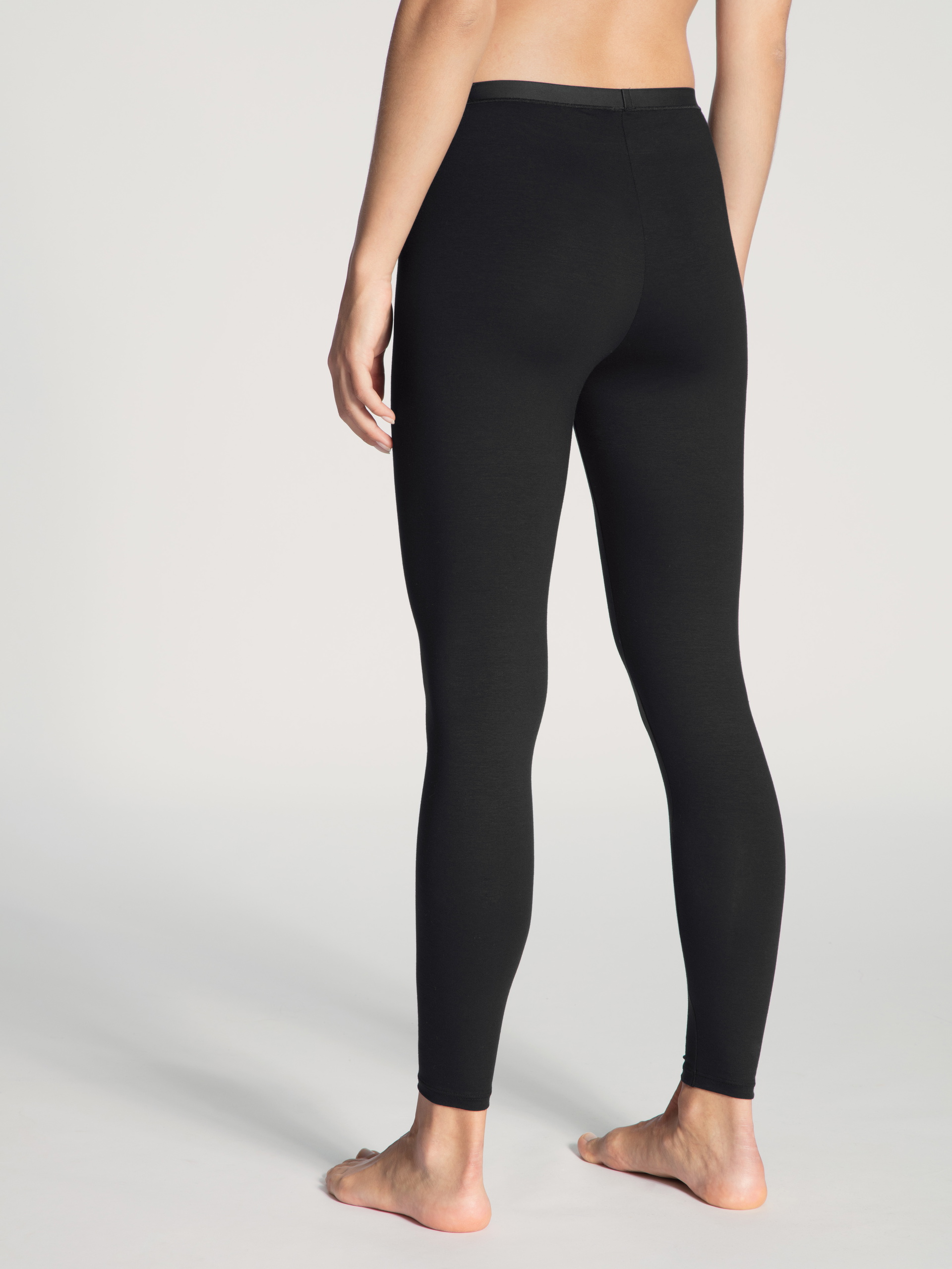 Damen-Model trägt Leggings aus Baumwolle in Schwarz, Einfarbig aus Serie Natural Comfort von CALIDA, Rückansicht