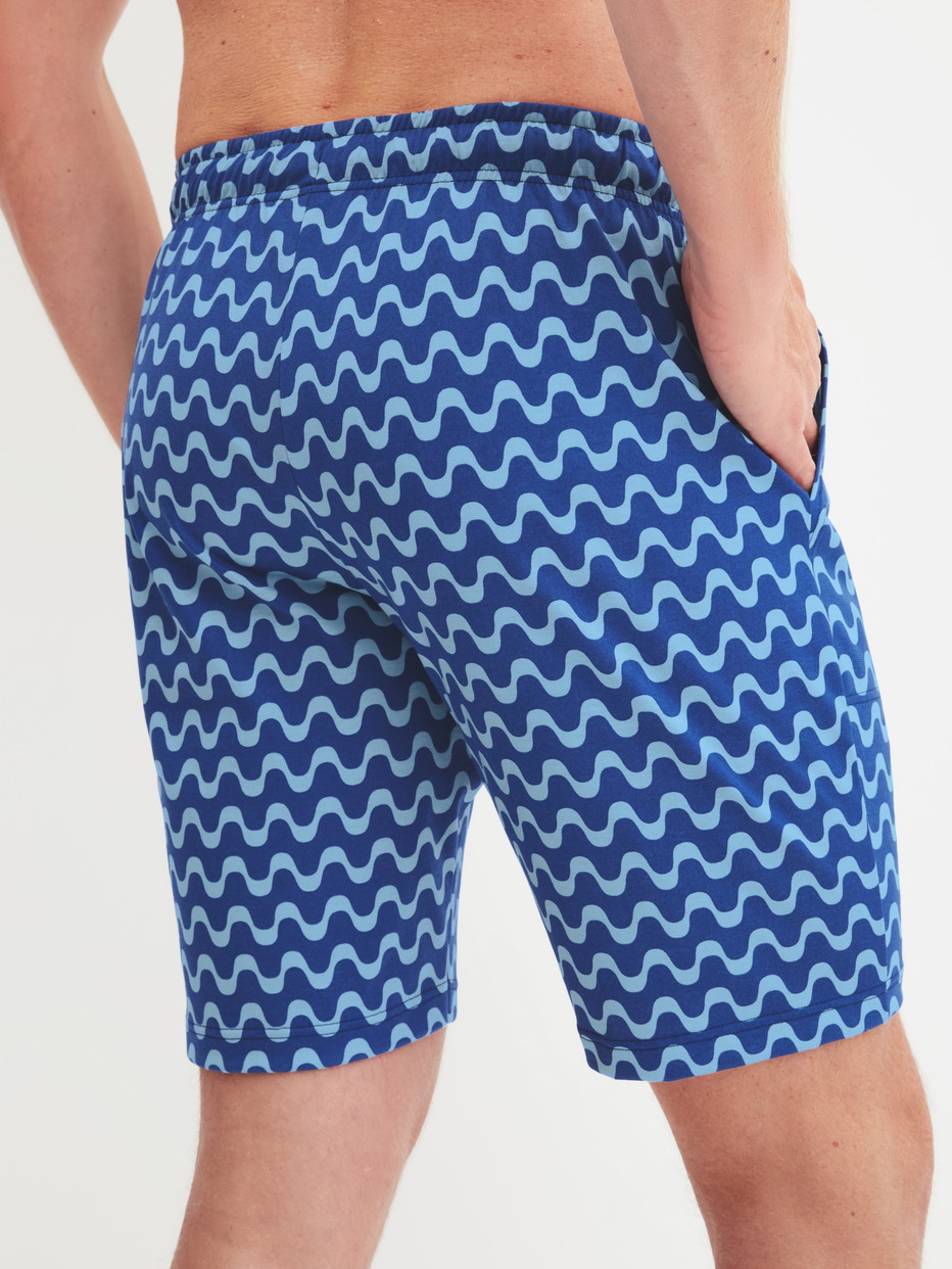 Herren-Model trägt Bermudas aus 100% Baumwolle in Blau, Gemustert aus Serie RMX Sleep Time off von CALIDA, Rückansicht