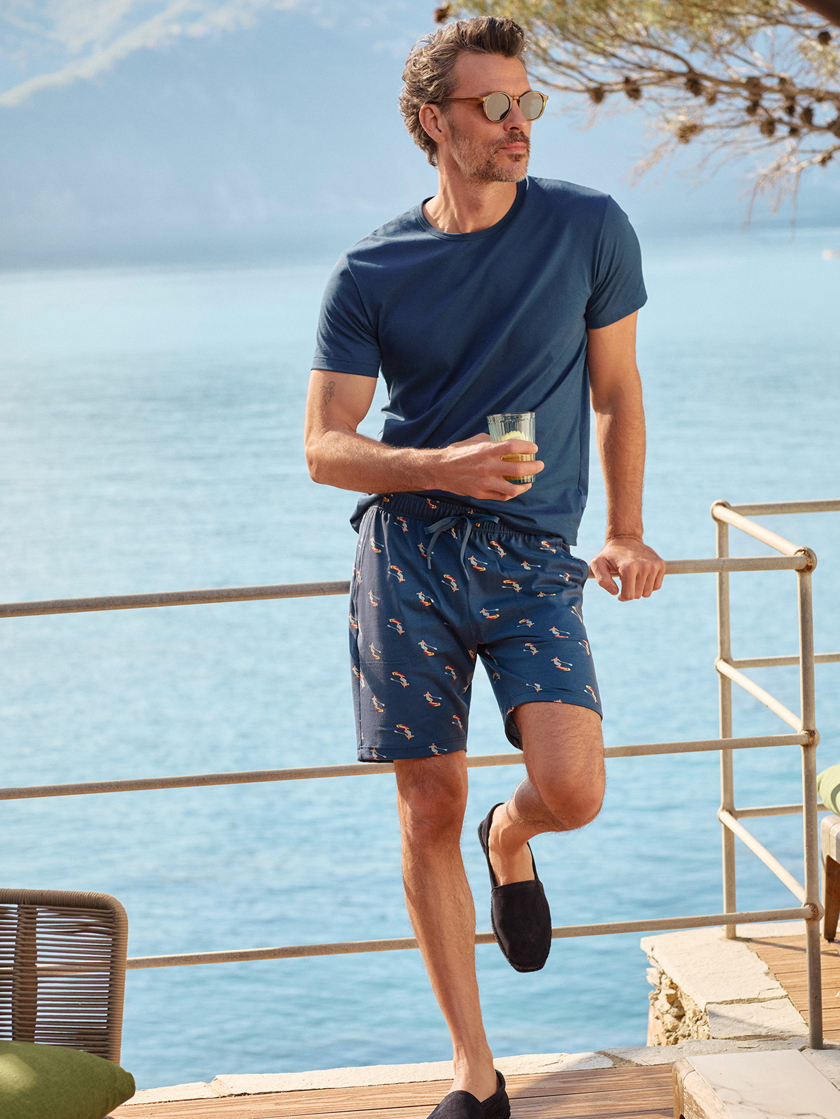 Herren-Model trägt Bermudas aus 100% Baumwolle in Blau, Gemustert aus Serie RMX Sleep Holiday von CALIDA, Zusatzbild