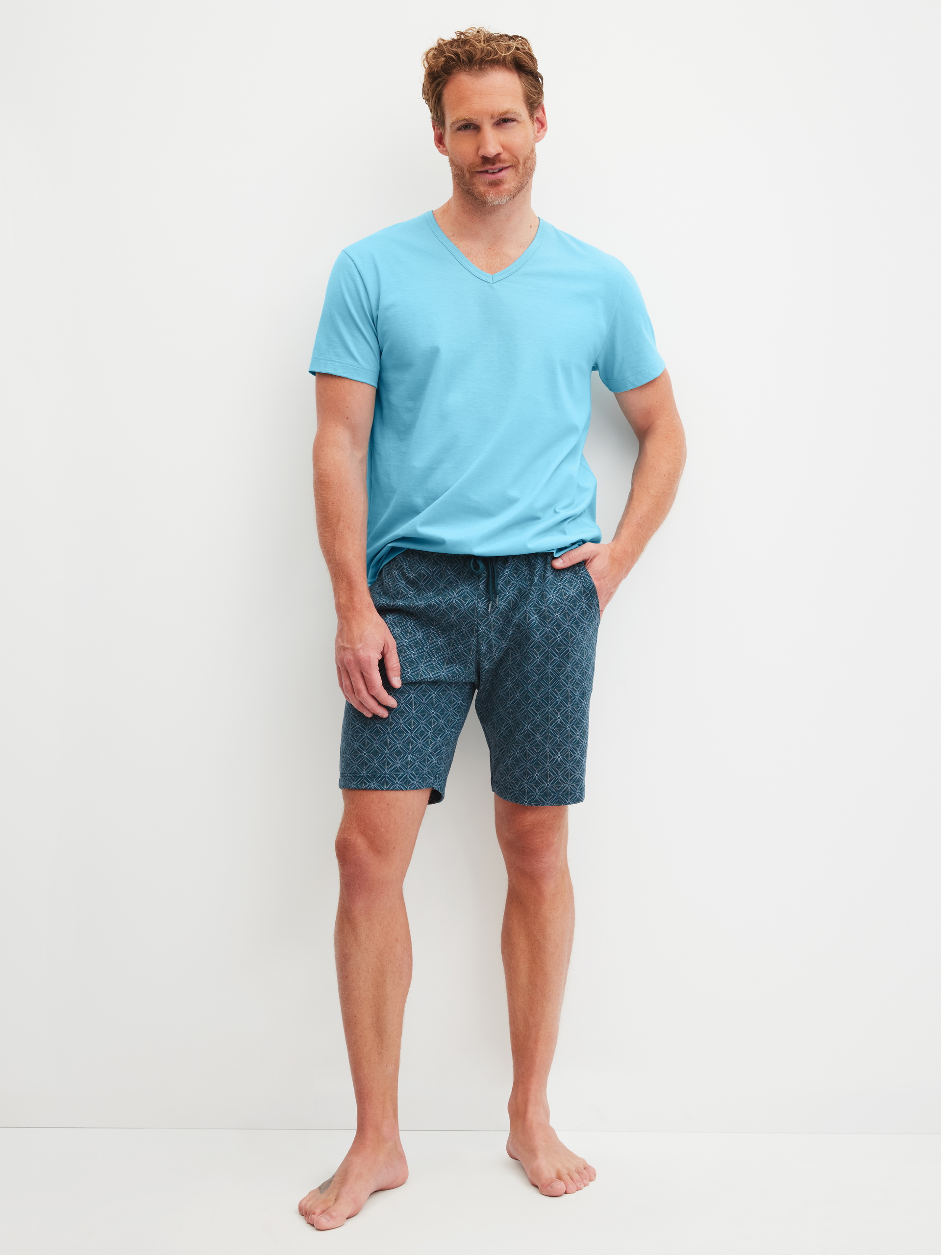 Herren-Model trägt Bermudas aus 100% Baumwolle in Türkis, Gemustert aus Serie RMX Sleep Leisure von CALIDA, Outfit