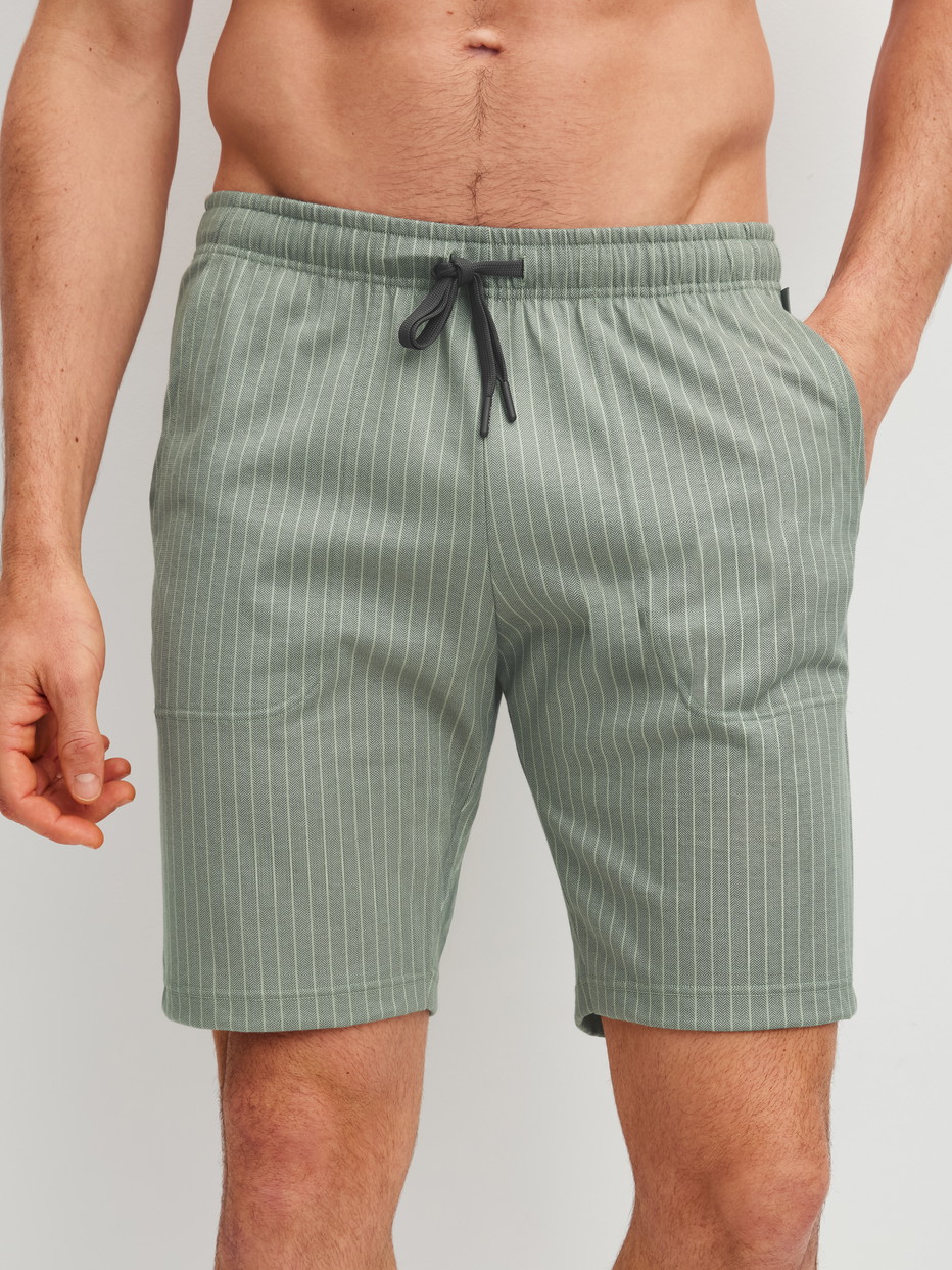 Herren-Model trägt Bermudas aus 100% Baumwolle in Grün, Einfarbig aus Serie RMX Sleep Leisure von CALIDA, Vorderansicht