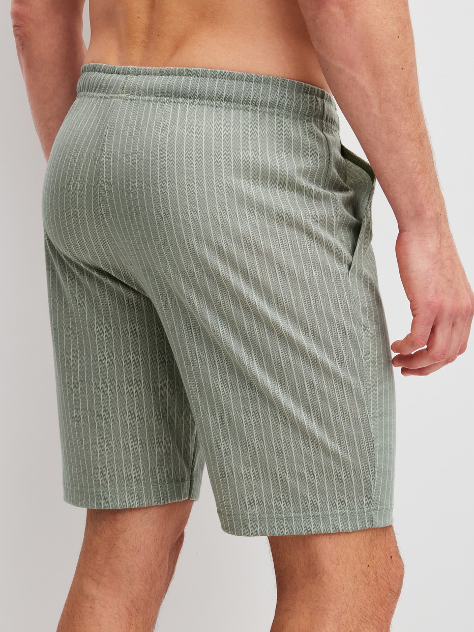 Herren-Model trägt Bermudas aus 100% Baumwolle in Grün, Einfarbig aus Serie RMX Sleep Leisure von CALIDA, Rückansicht