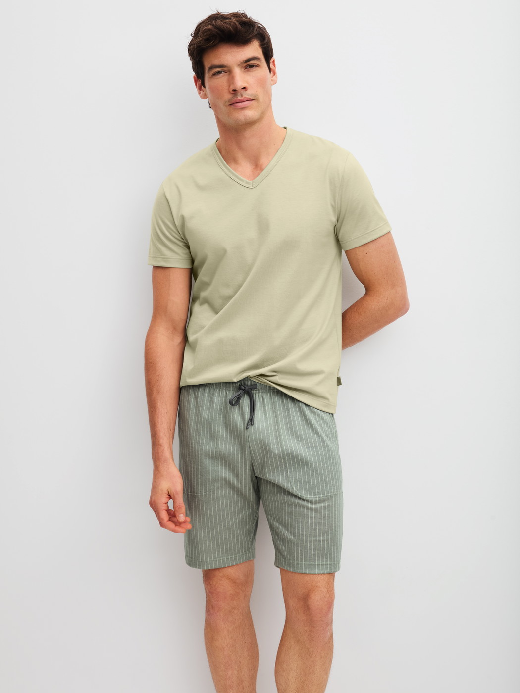 Herren-Model trägt Bermudas aus 100% Baumwolle in Grün, Einfarbig aus Serie RMX Sleep Leisure von CALIDA, Outfit