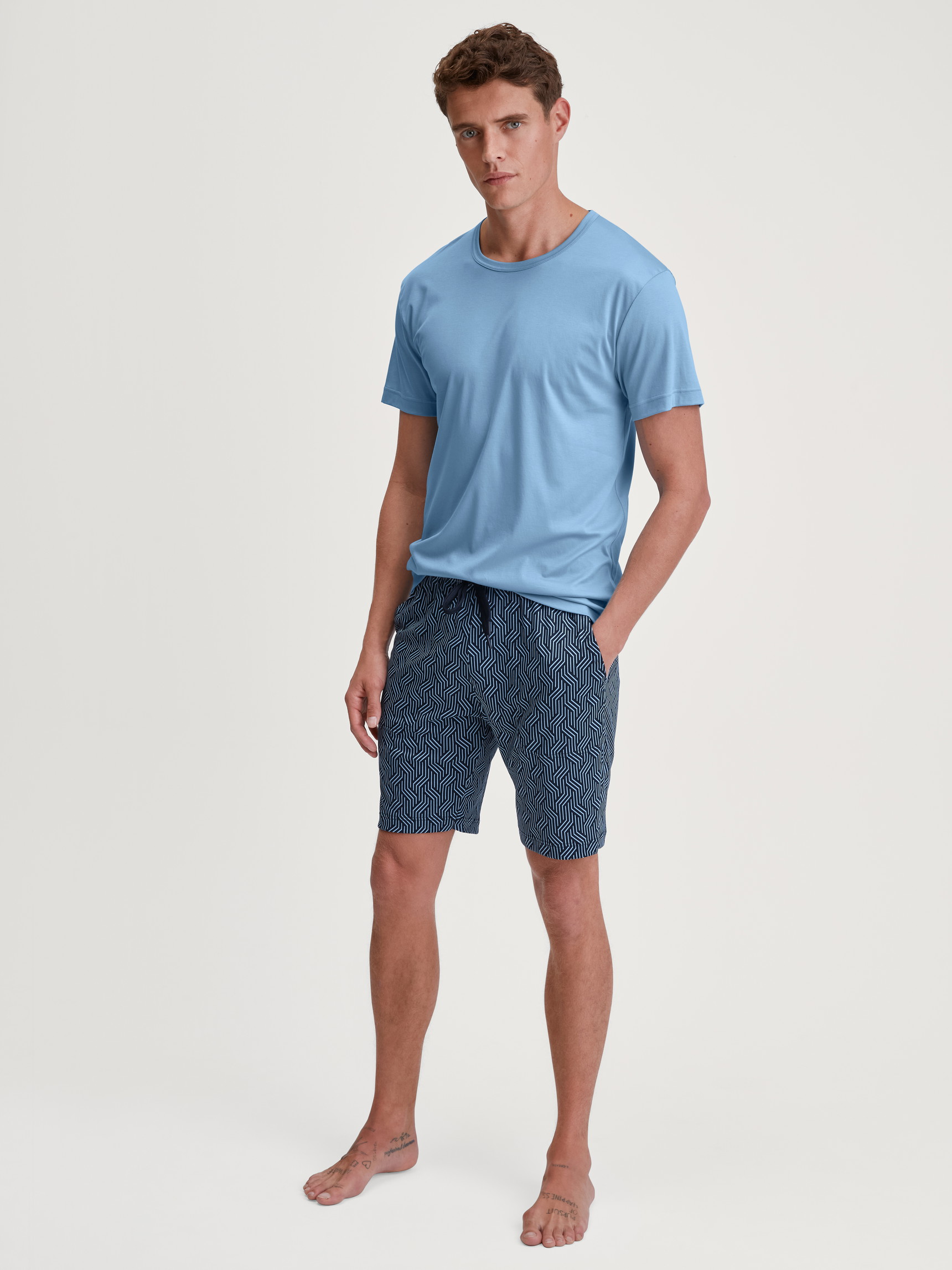 Men model is wearing Bermudas with side pockets made of Cotton in Blue, Patterned from the RMX Sleep Free series by CALIDA, Outfit