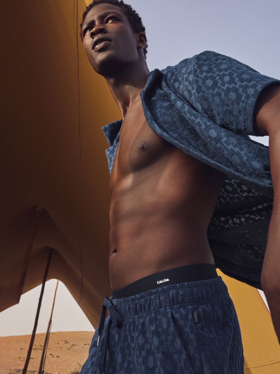 Men model is wearing Bermudas made of Cotton in Blue, Unicoloured from the RMX Lounge Holiday series by CALIDA