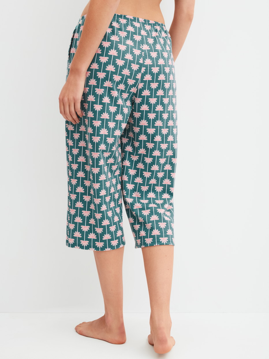 Damen-Model trägt 3/4-Pyjamahose aus 100% Baumwolle in Türkis, Gemustert aus Serie Favourites Beach von CALIDA, Rückansicht