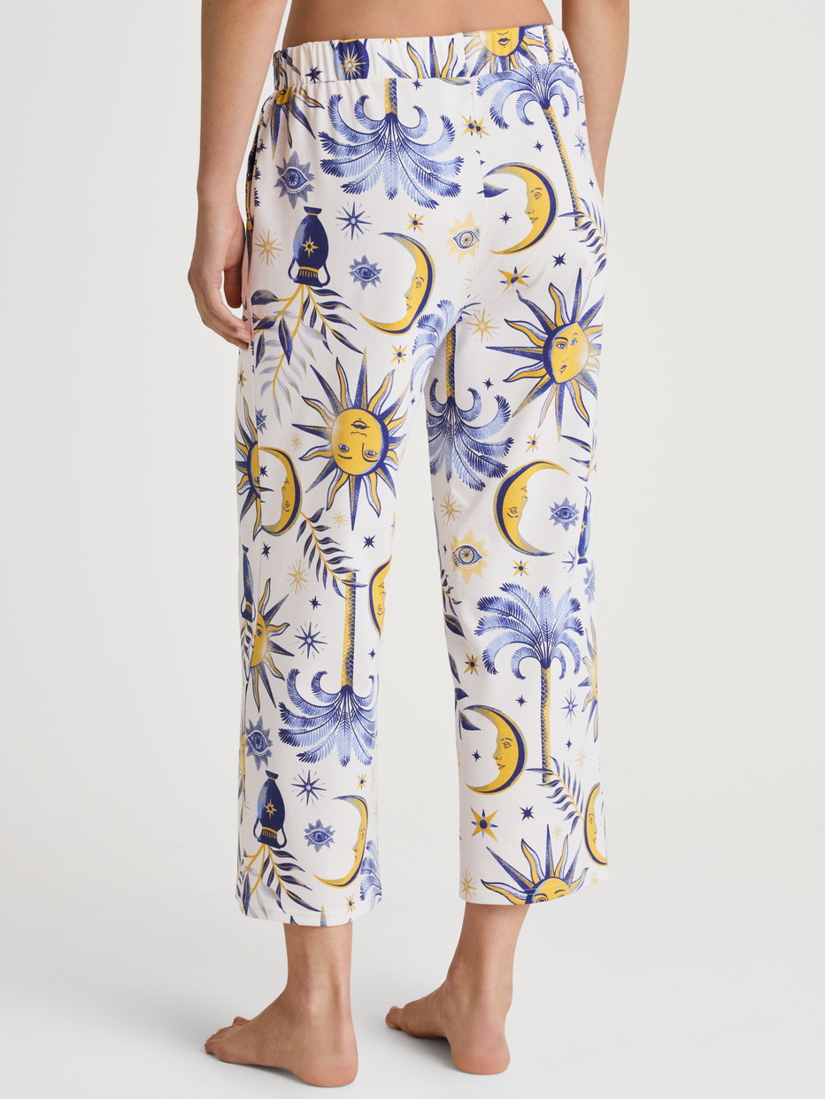 La modella / Il modello Donna indossa 7/8 pantaloni da pigiama in 100% cotone di colore Blu, Floreale, della serie Favourites Magic di CALIDA, Vista posteriore