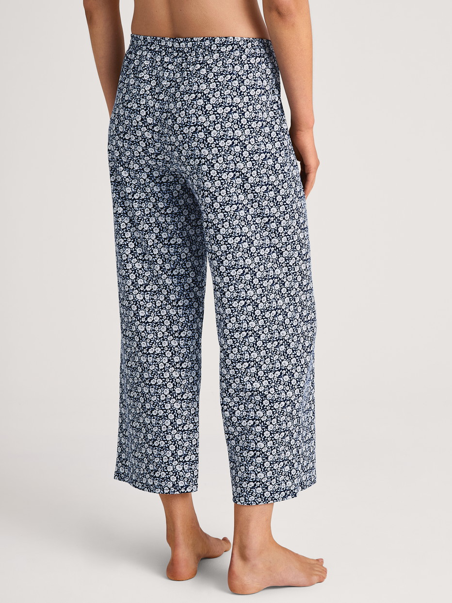 Women model is wearing 7/8 Pyjama bottom made of 100% Cotton in Blue, Floral from the Favourites Sleep series by CALIDA, Back view