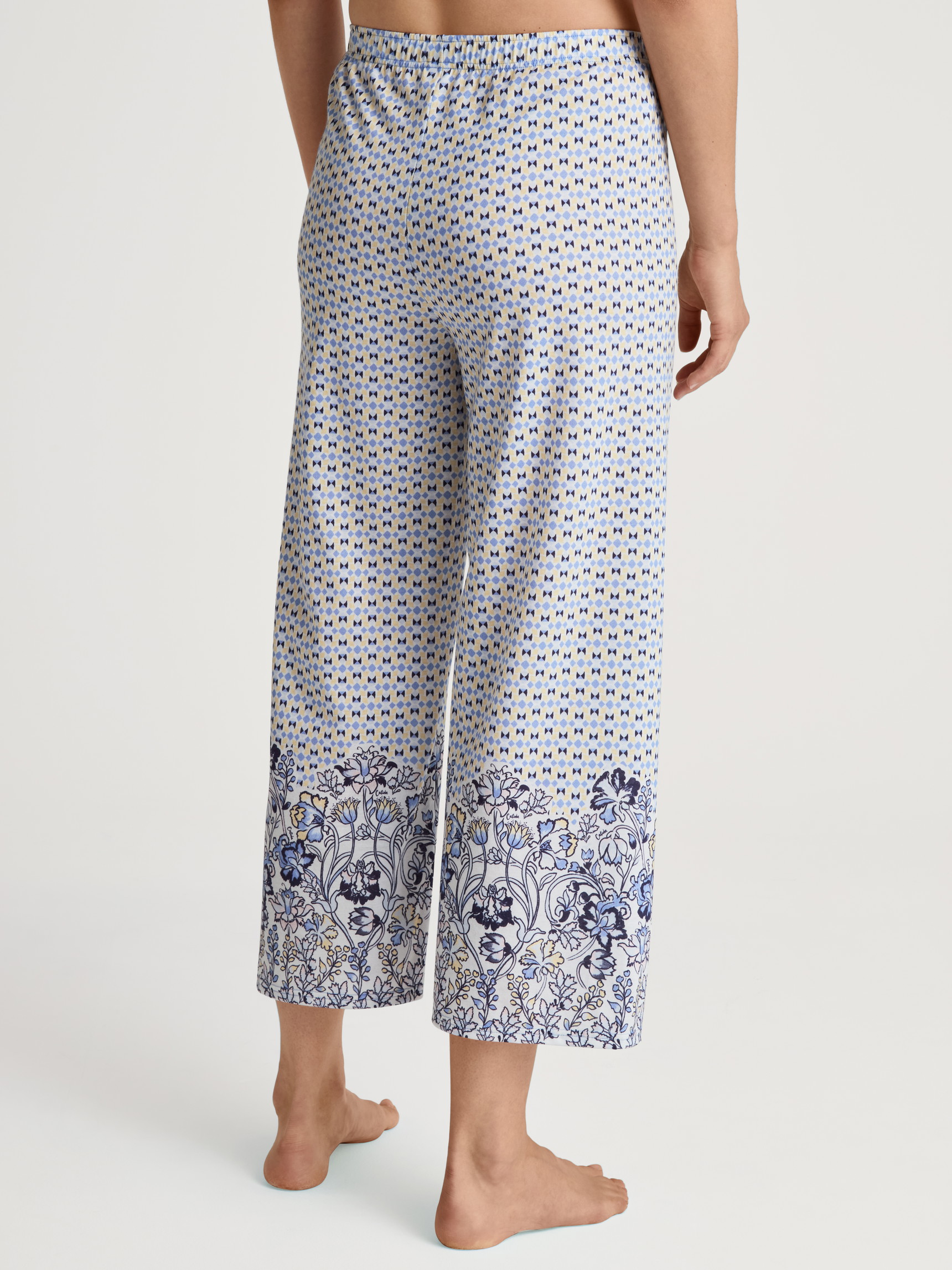 Women model is wearing 7/8 pants made of Modal in Blue, Floral from the Favourites Joy series by CALIDA, Back view
