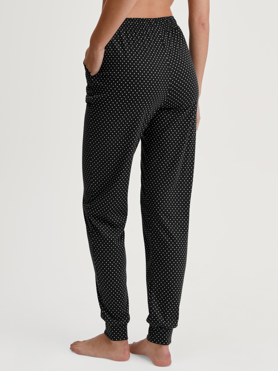 Damen-Model trägt Pyjamahose mit Bündchen aus Baumwolle in Schwarz, Gemustert aus Serie Favourites Journey von CALIDA, Rückansicht