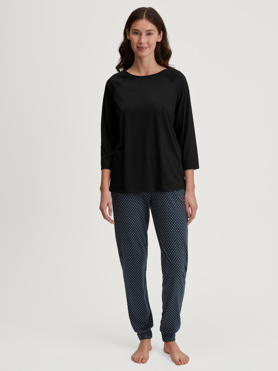 Damen-Model trägt Pyjamahose mit Bündchen aus Baumwolle in Schwarz, Gemustert aus Serie Favourites Journey von CALIDA, Outfit
