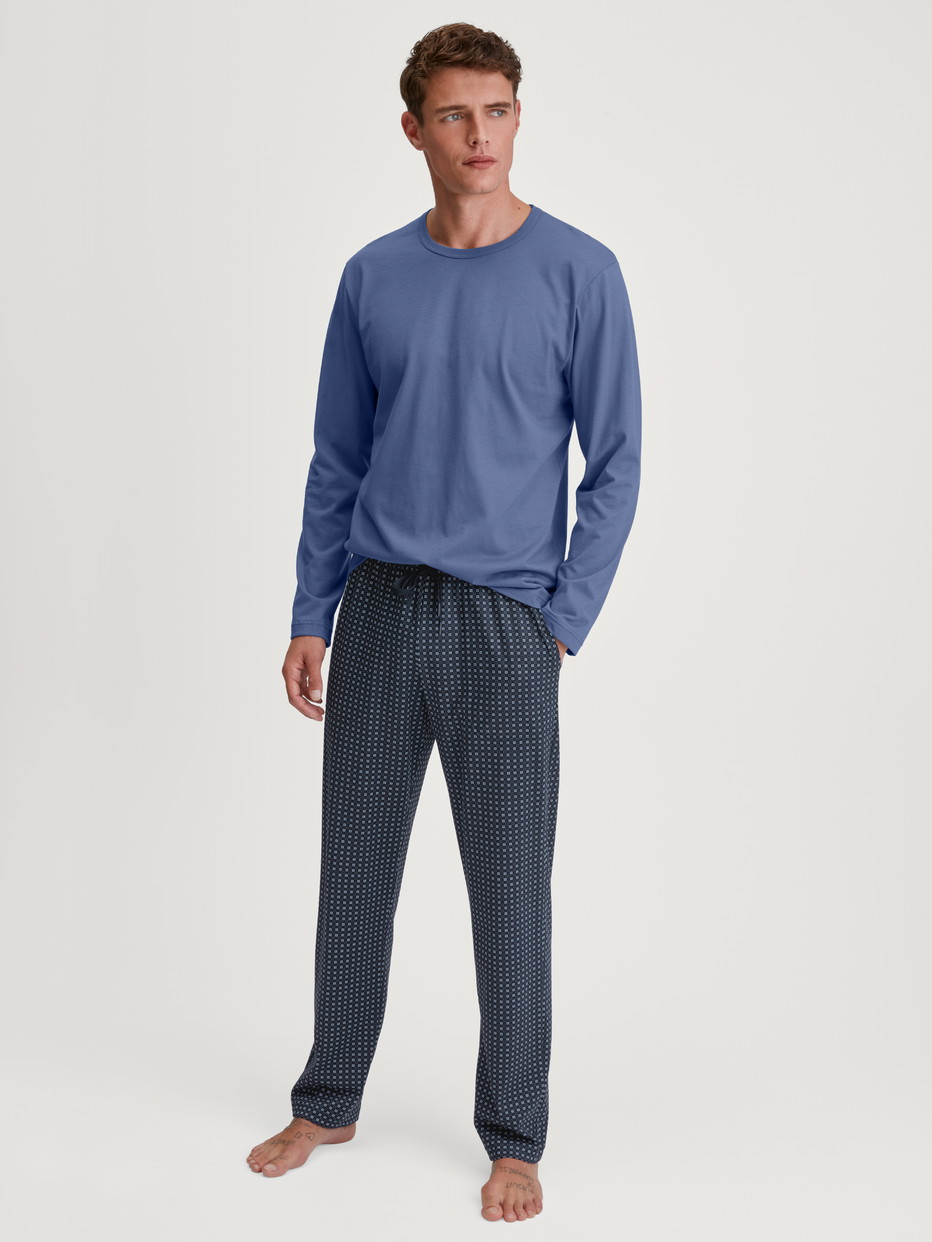 Herren-Model trägt Pyjamahose mit Seitentaschen aus 100% Baumwolle in Blau, Kariert aus Serie Remix Basic Sleep von CALIDA, Outfit