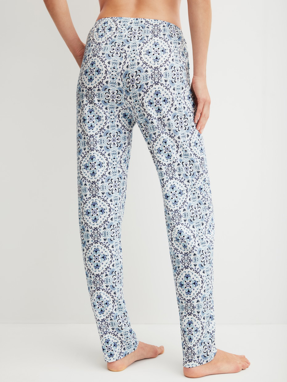Damen-Model trägt Pyjamahose mit Seitentaschen aus 100% Baumwolle in Blau, Gemustert aus Serie Favourites Tiles von CALIDA, Rückansicht