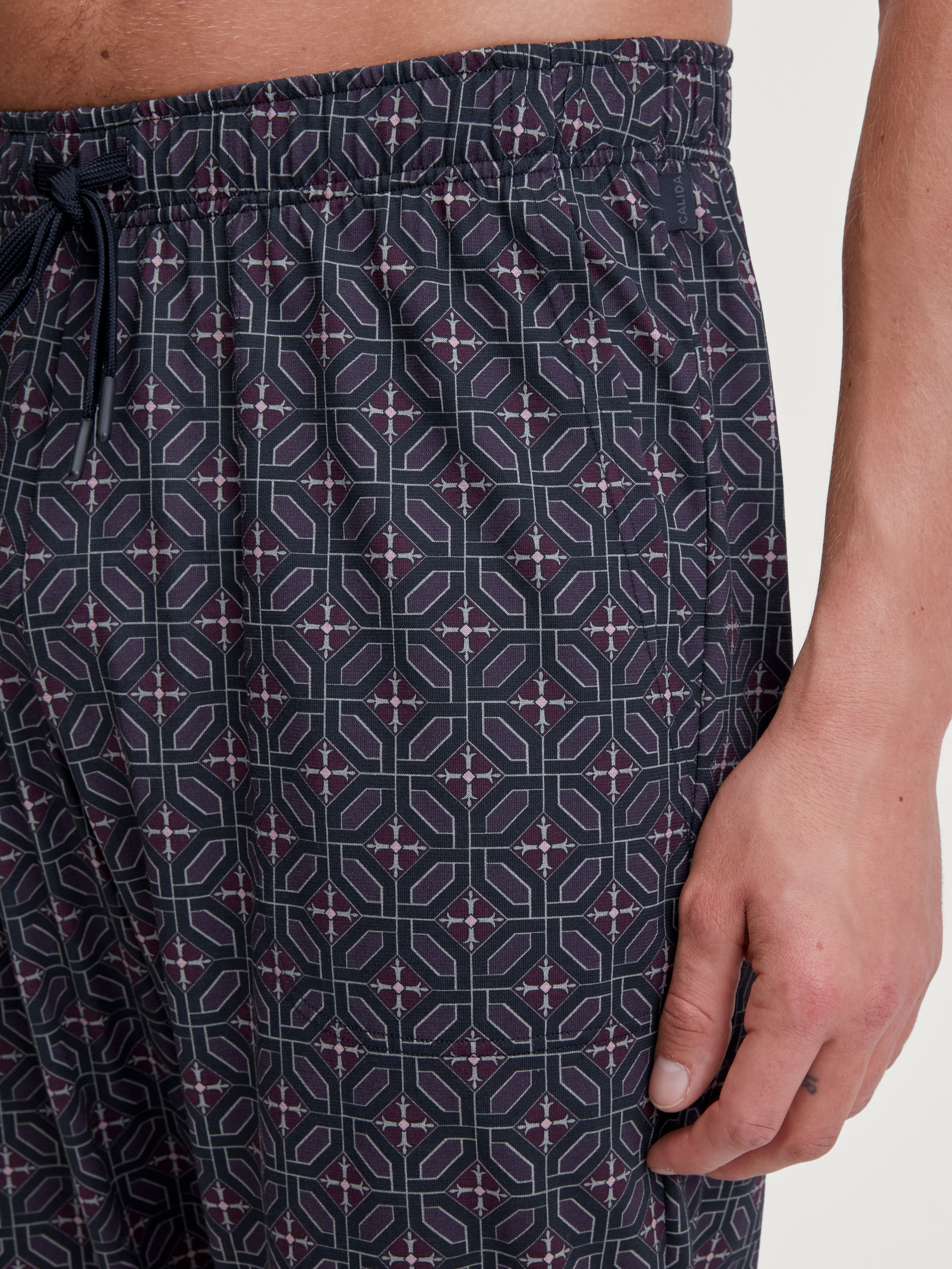 Herren-Model trägt Pyjamahose mit Seitentaschen aus 100% Baumwolle in Braun, Gemustert aus Serie RMX Sleep Holiday von CALIDA, Detail