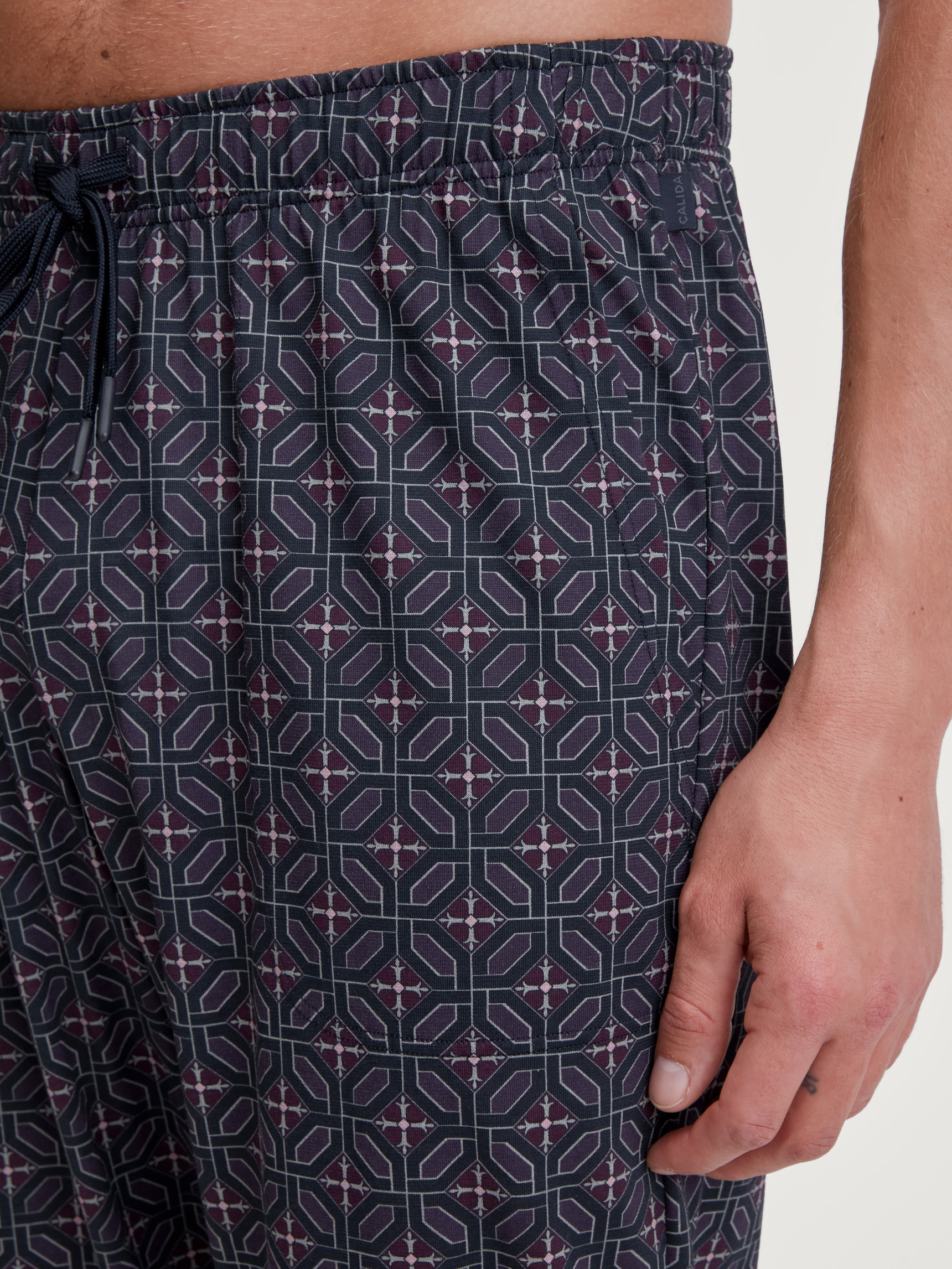 Herren-Model trägt Pyjamahose mit Seitentaschen aus 100% Baumwolle in Braun, Gemustert aus Serie RMX Sleep Holiday von CALIDA, Detail