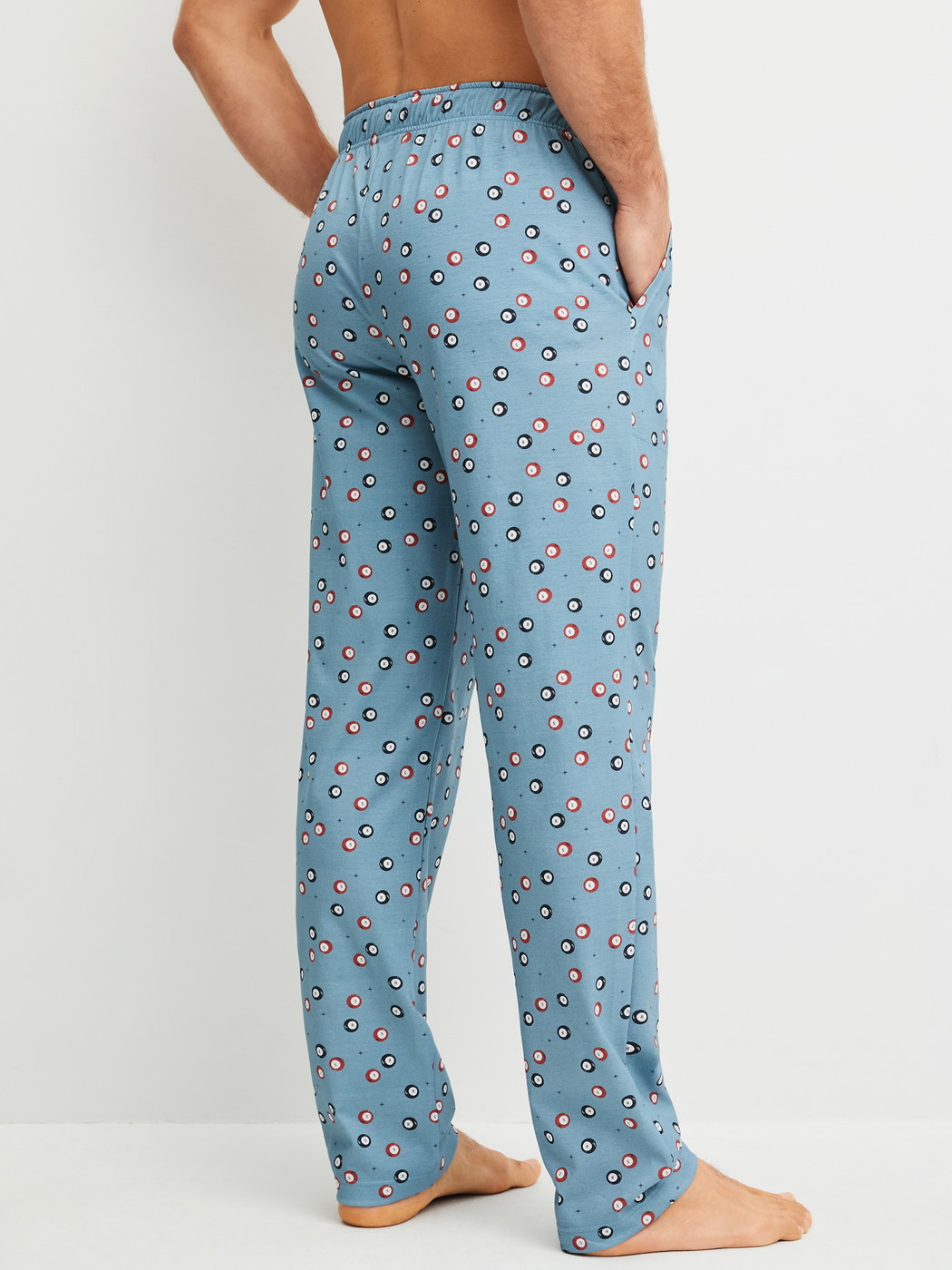 Men model is wearing Pyjama Bottoms with Side Pockets made of 100% Cotton in Blue, Patterned from the RMX Sleep Holiday series by CALIDA, Back view