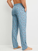 Men model is wearing Pyjama Bottoms with Side Pockets made of 100% Cotton in Blue, Patterned from the RMX Sleep Holiday series by CALIDA, Back view