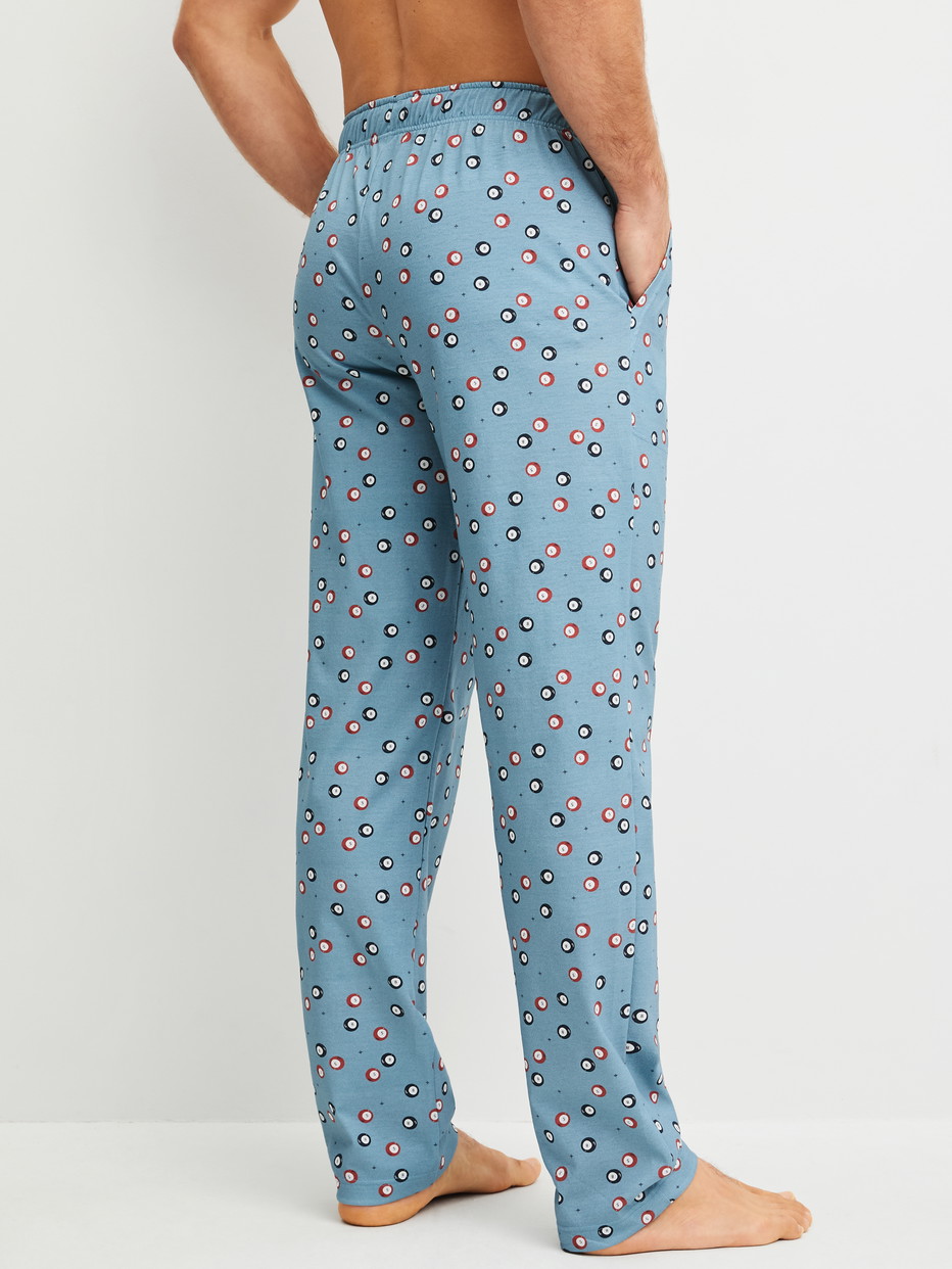 Herren-Model trägt Pyjamahose mit Seitentaschen aus 100% Baumwolle in Blau, Gemustert aus Serie RMX Sleep Holiday von CALIDA, Rückansicht