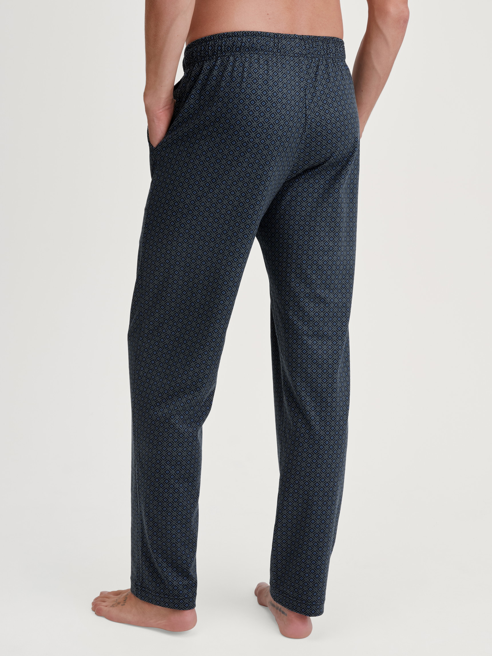 Men model is wearing Pyjama Bottoms with Side Pockets made of 100% Cotton in Blue, Patterned from the RMX Sleep Weekend series by CALIDA, Back view