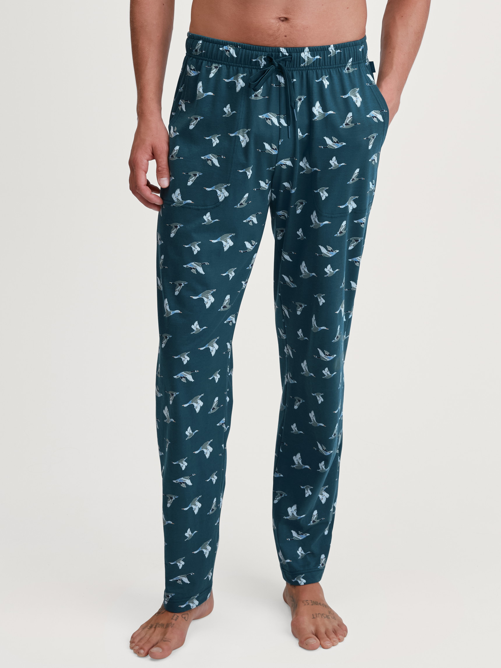Herren-Model trägt Pyjamahose mit Seitentaschen aus 100% Baumwolle in Grün, Gemustert aus Serie RMX Sleep Weekend von CALIDA, Vorderansicht