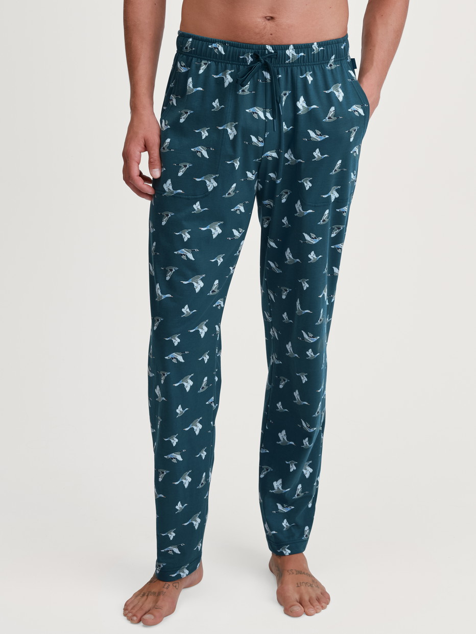 Herren-Model trägt Pyjamahose mit Seitentaschen aus 100% Baumwolle in Grün, Gemustert aus Serie RMX Sleep Weekend von CALIDA, Vorderansicht
