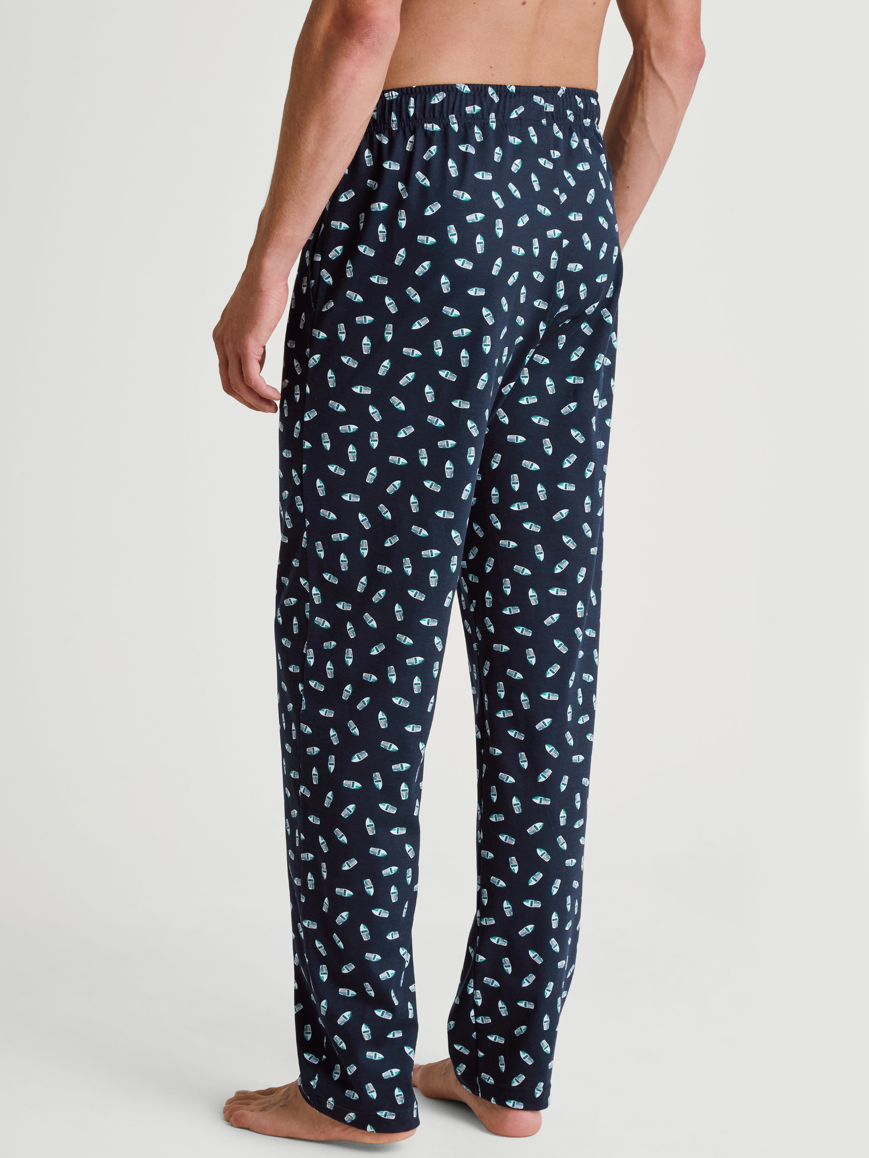 Herren-Model trägt Pyjamahose mit Seitentaschen aus 100% Baumwolle in Blau, Motiv aus Serie RMX Sleep Weekend von CALIDA, Rückansicht