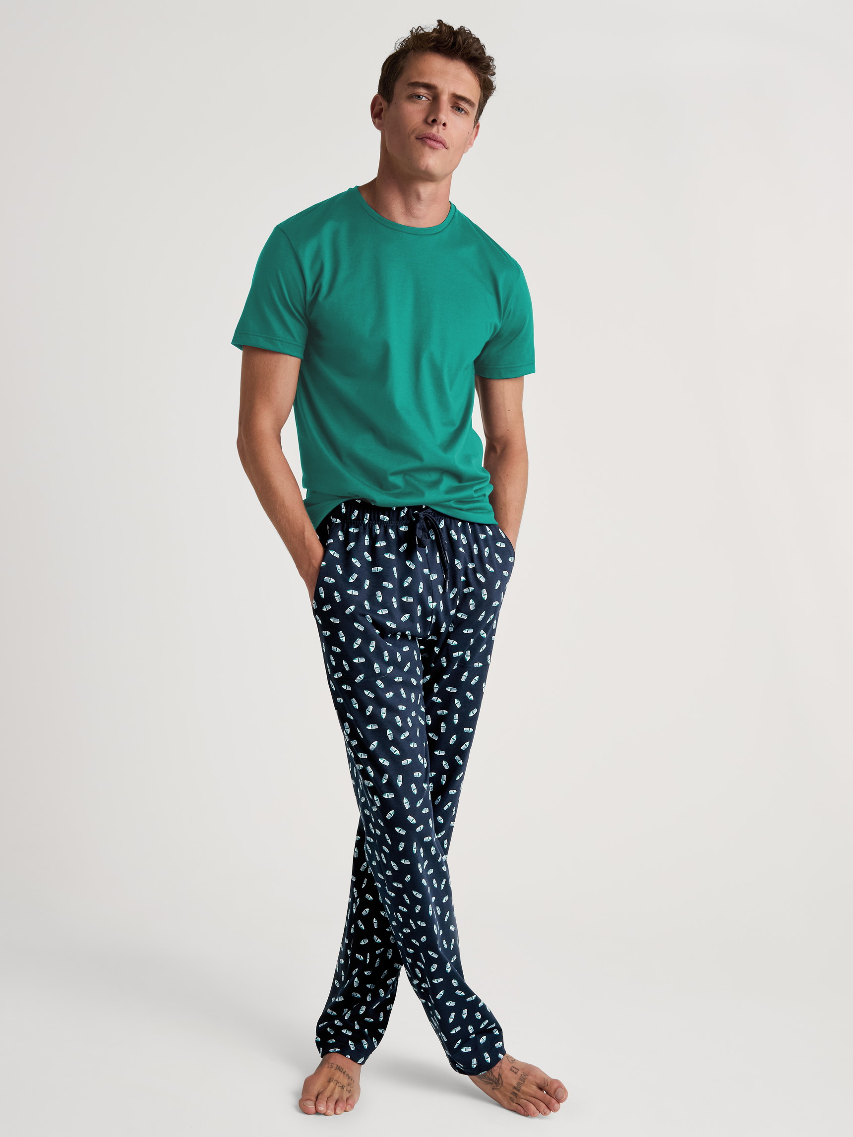 Herren-Model trägt Pyjamahose mit Seitentaschen aus 100% Baumwolle in Blau, Motiv aus Serie RMX Sleep Weekend von CALIDA, Outfit