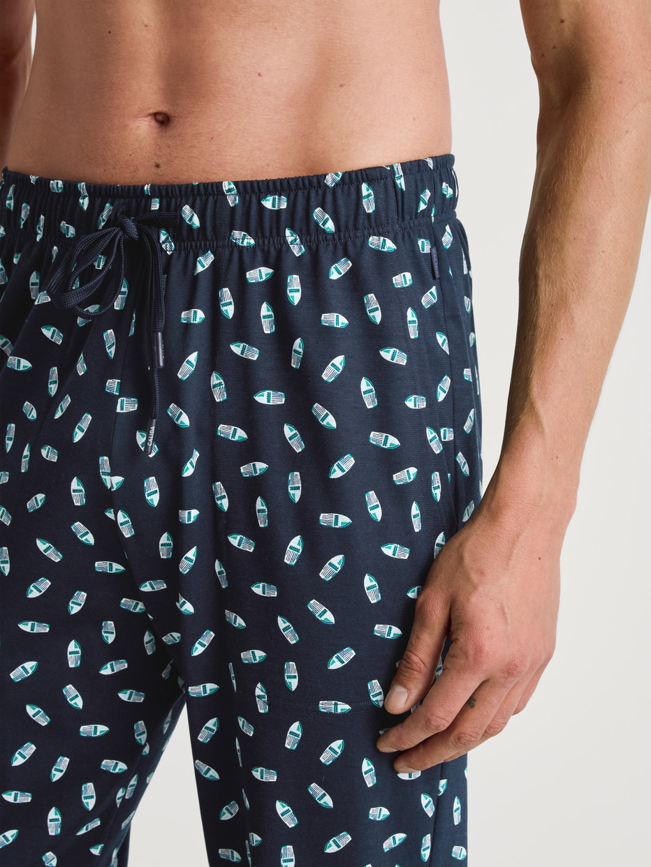 La modella / Il modello Uomo indossa Pantaloni da notte con tasche in 100% cotone di colore Blu, Motivo, della serie RMX Sleep Weekend di CALIDA, Dettaglio