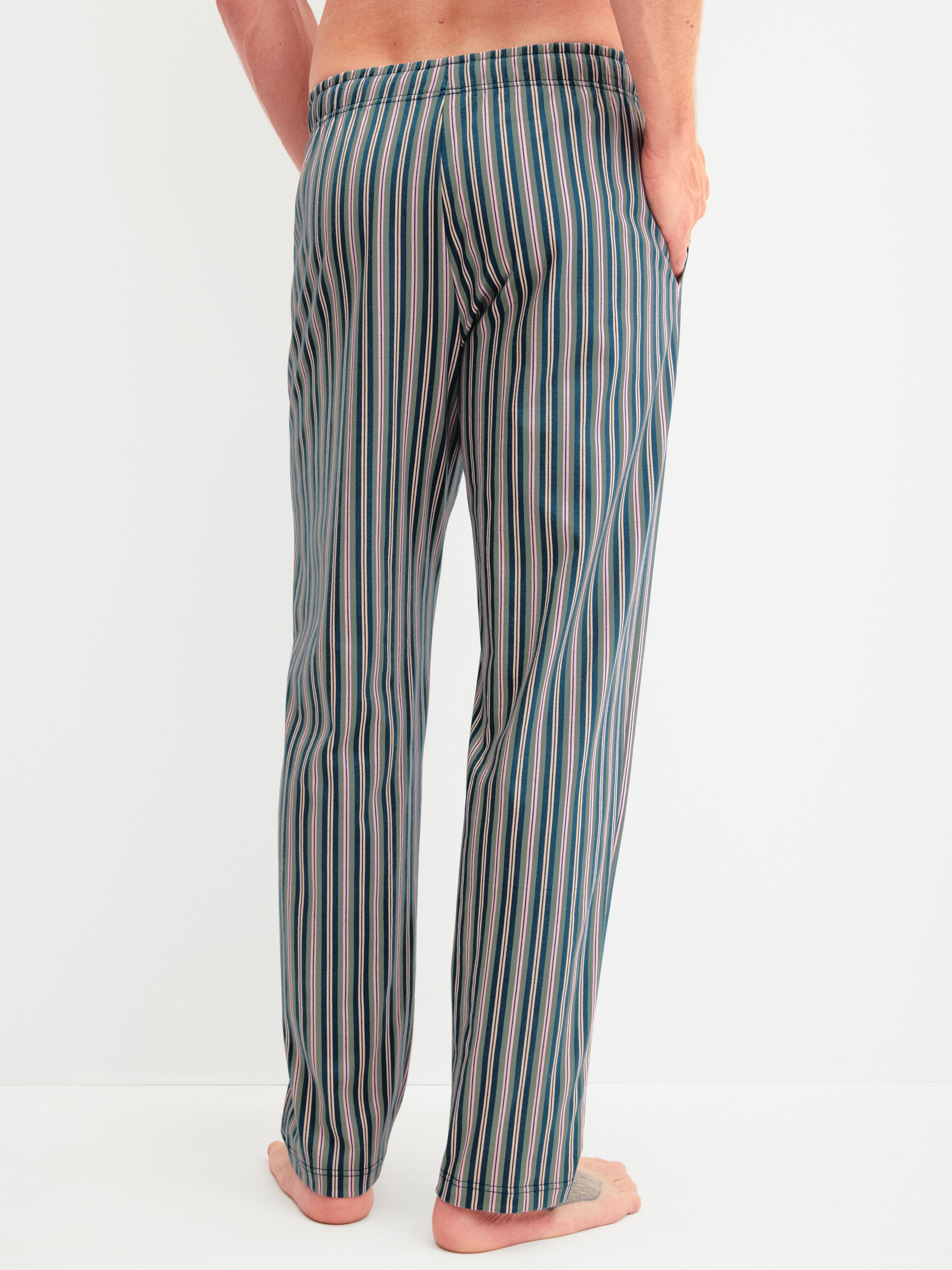 Herren-Model trägt Pyjamahose mit Seitentaschen aus 100% Baumwolle in Grün, Gestreift aus Serie RMX Sleep Leisure von CALIDA, Rückansicht