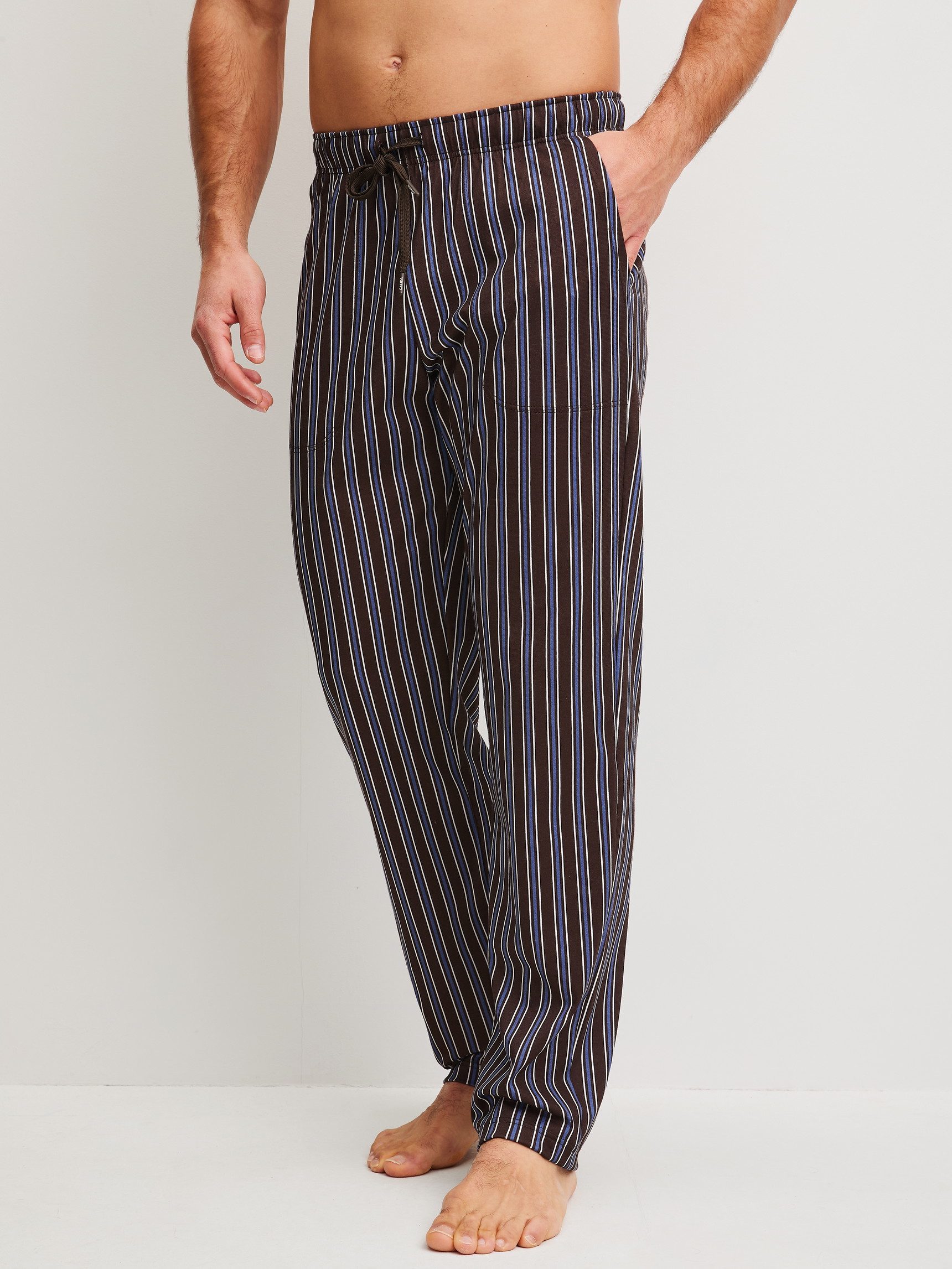 Men model is wearing Pyjama Bottoms with Side Pockets made of 100% Cotton in Brown, Striped from the RMX Sleep Weekend series by CALIDA, Front view