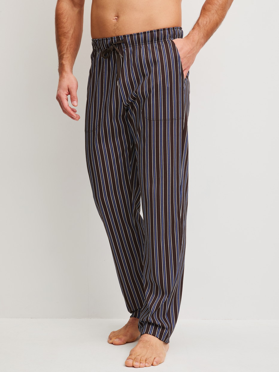 Herren-Model trägt Pyjamahose mit Seitentaschen aus 100% Baumwolle in Braun, Gestreift aus Serie RMX Sleep Weekend von CALIDA, Vorderansicht