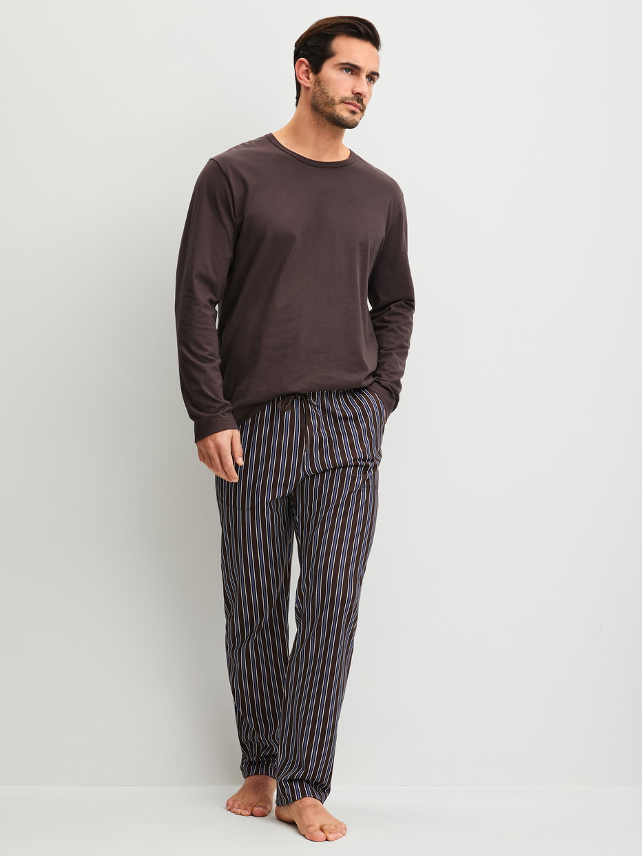 Herren-Model trägt Pyjamahose mit Seitentaschen aus 100% Baumwolle in Braun, Gestreift aus Serie RMX Sleep Weekend von CALIDA, Outfit