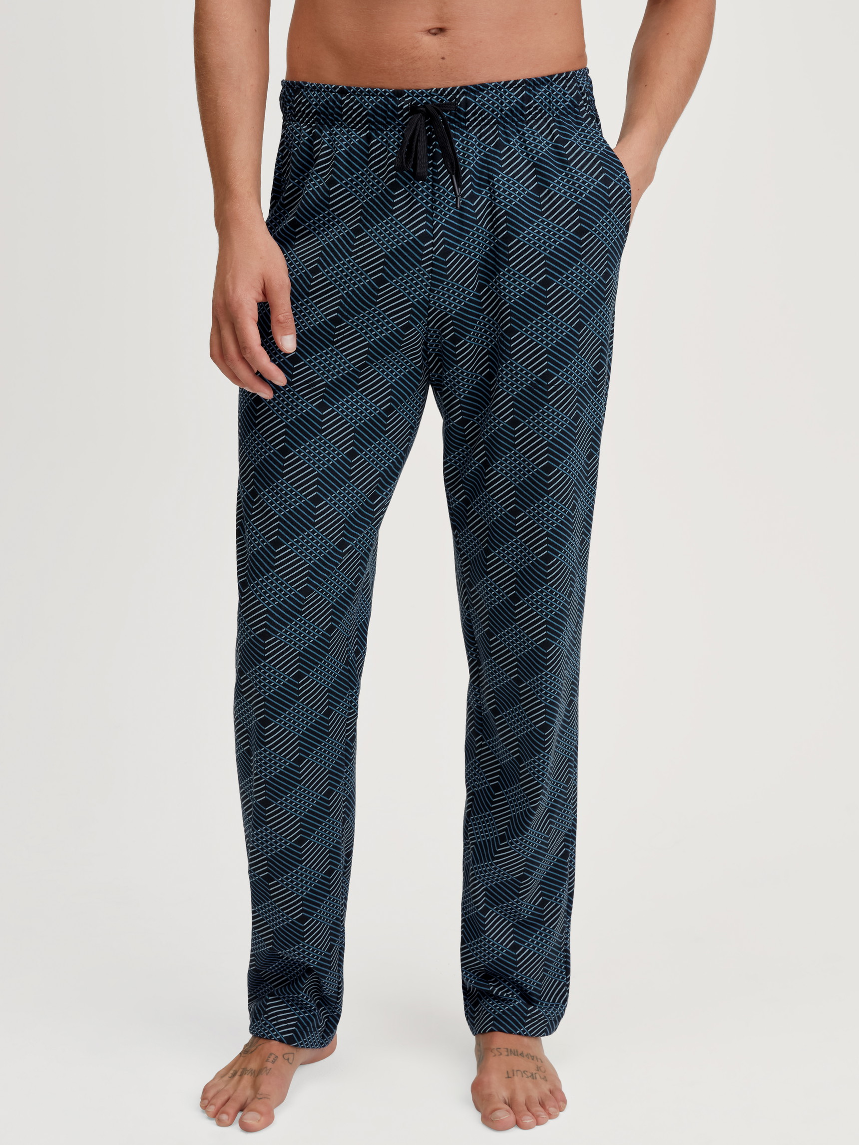 Herren-Model trägt Pyjamahose mit Seitentaschen aus 100% Baumwolle in Schwarz, Gemustert aus Serie RMX Sleep Leisure von CALIDA, Vorderansicht
