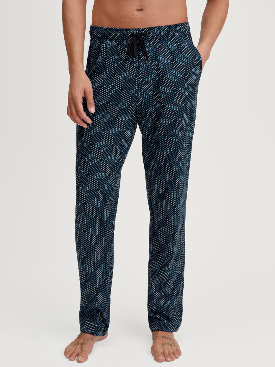 Herren-Model trägt Pyjamahose mit Seitentaschen aus 100% Baumwolle in Schwarz, Gemustert aus Serie RMX Sleep Leisure von CALIDA, Vorderansicht