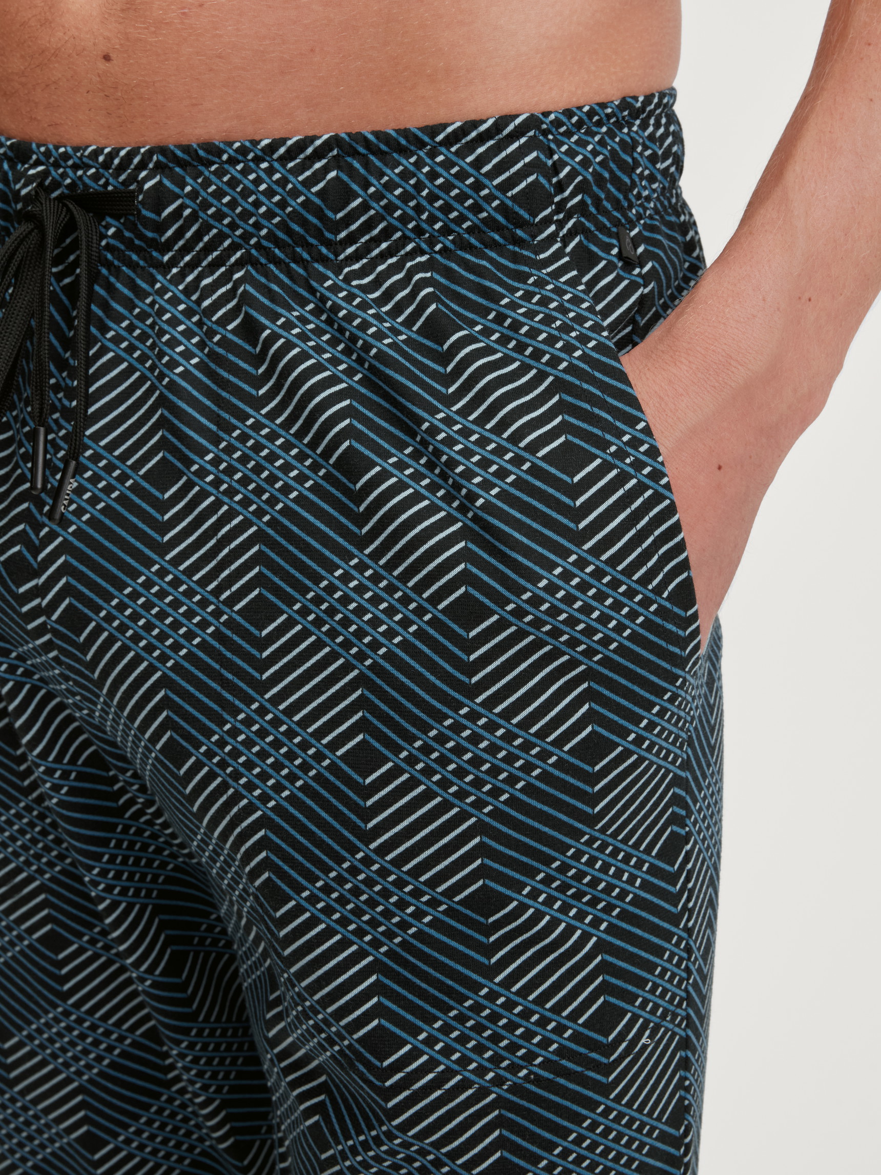Herren-Model trägt Pyjamahose mit Seitentaschen aus 100% Baumwolle in Schwarz, Gemustert aus Serie RMX Sleep Leisure von CALIDA, Detail