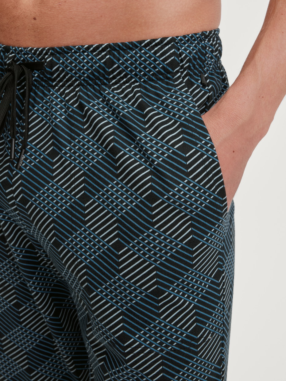 Herren-Model trägt Pyjamahose mit Seitentaschen aus 100% Baumwolle in Schwarz, Gemustert aus Serie RMX Sleep Leisure von CALIDA, Detail