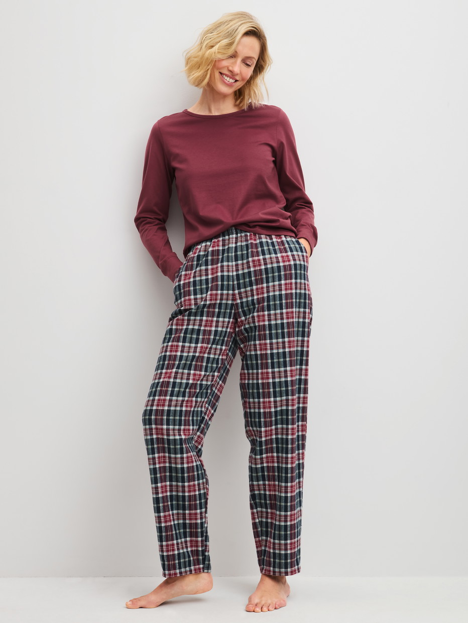 La modella / Il modello Donna indossa Pantaloni in flanella con tasche laterali in 100% cotone di colore Blu, A scacchi, della serie PJ Party M&M di CALIDA, Abbigliamento