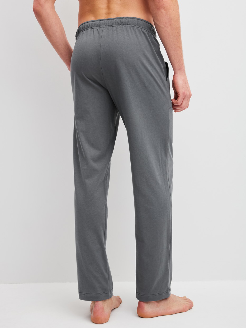 Herren-Model trägt Pyjamahose mit Seitentaschen aus 100% Baumwolle in Grau, Einfarbig aus Serie RMX Sleep Leisure von CALIDA, Rückansicht